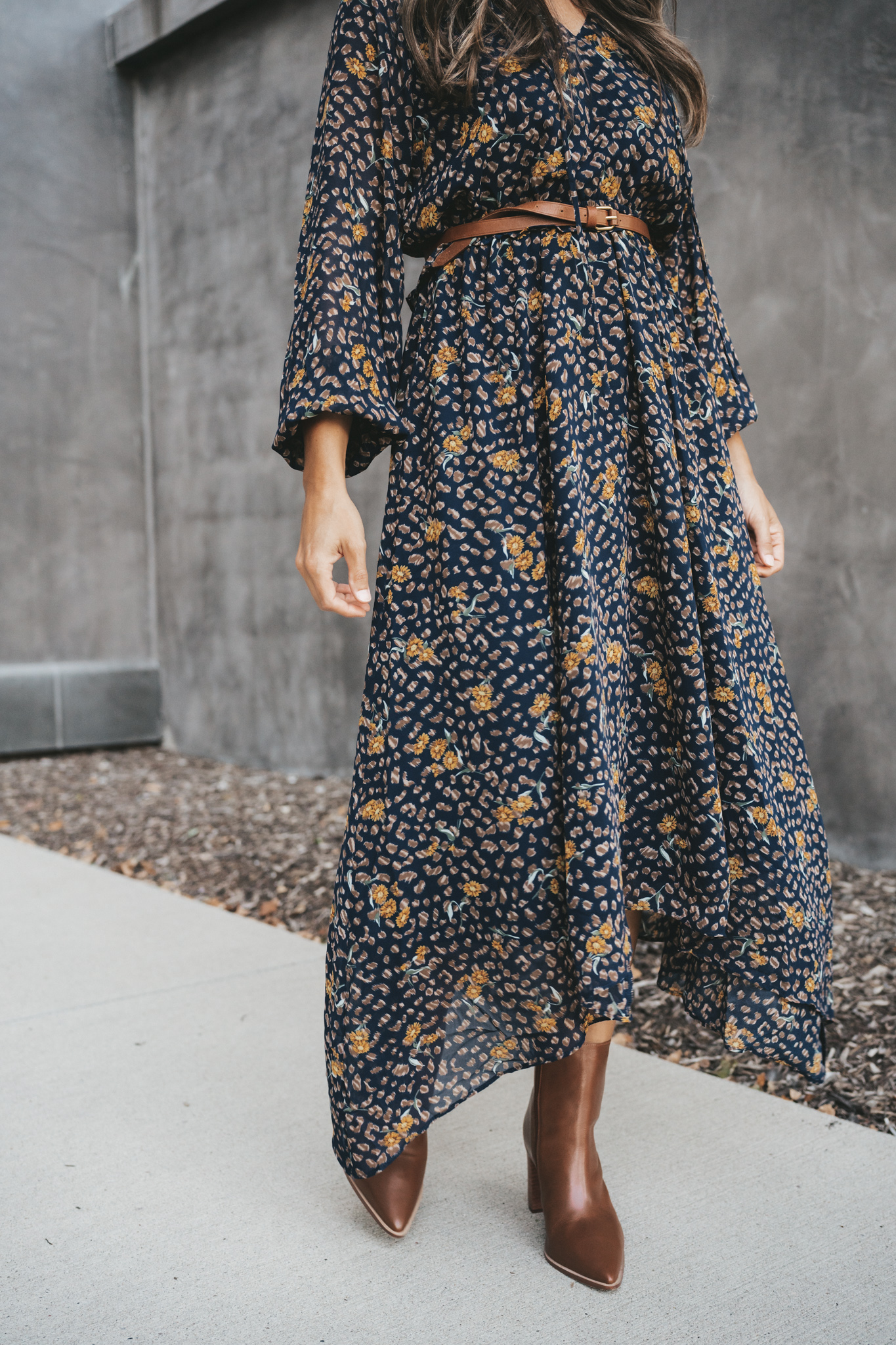 ashley wearing a navy floral midi dress belted at the waist and brown ankle boots
