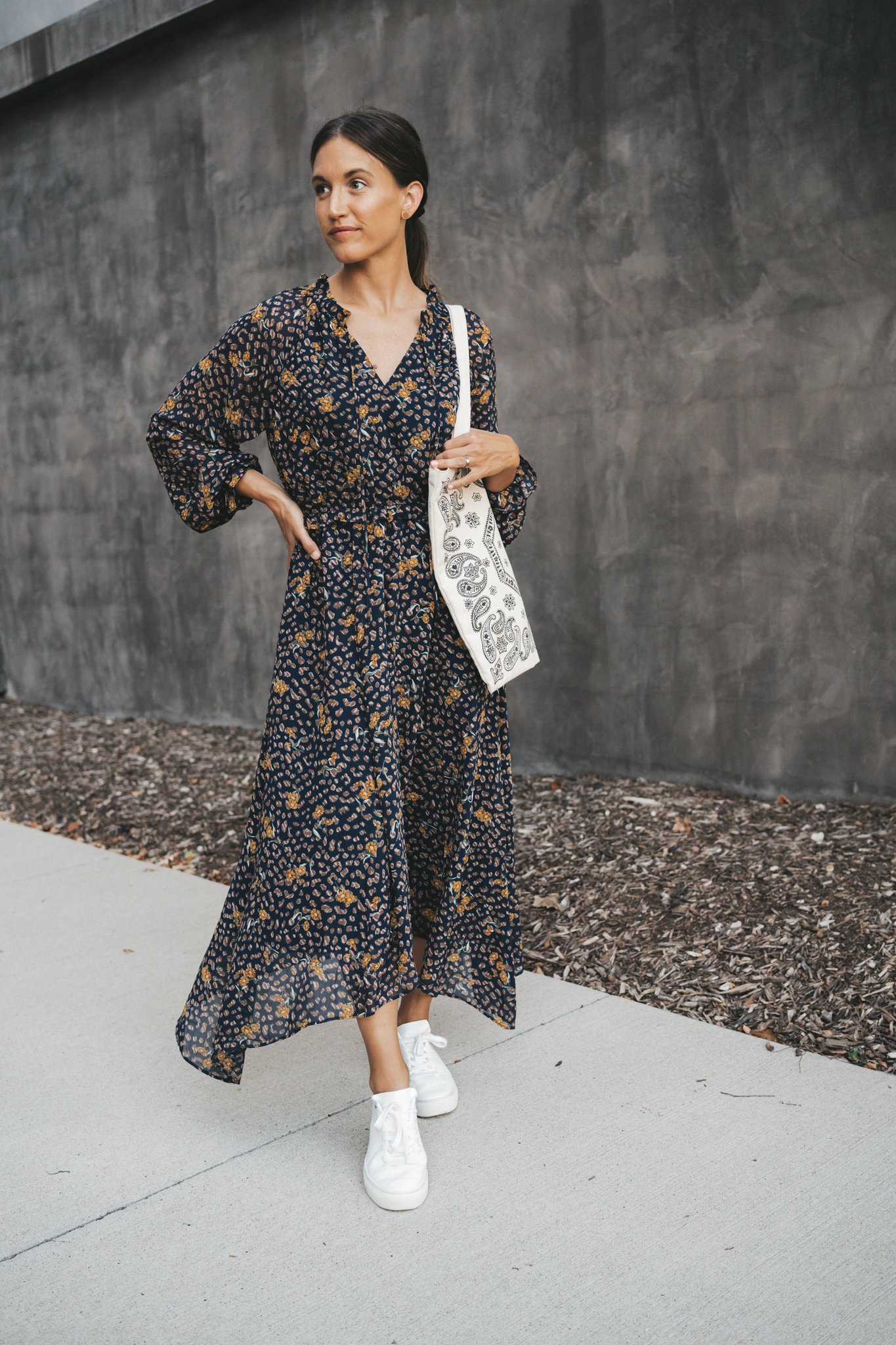 ashley wearing a navy blue floral midi dress, paisley canvas tote bag and white sneakers