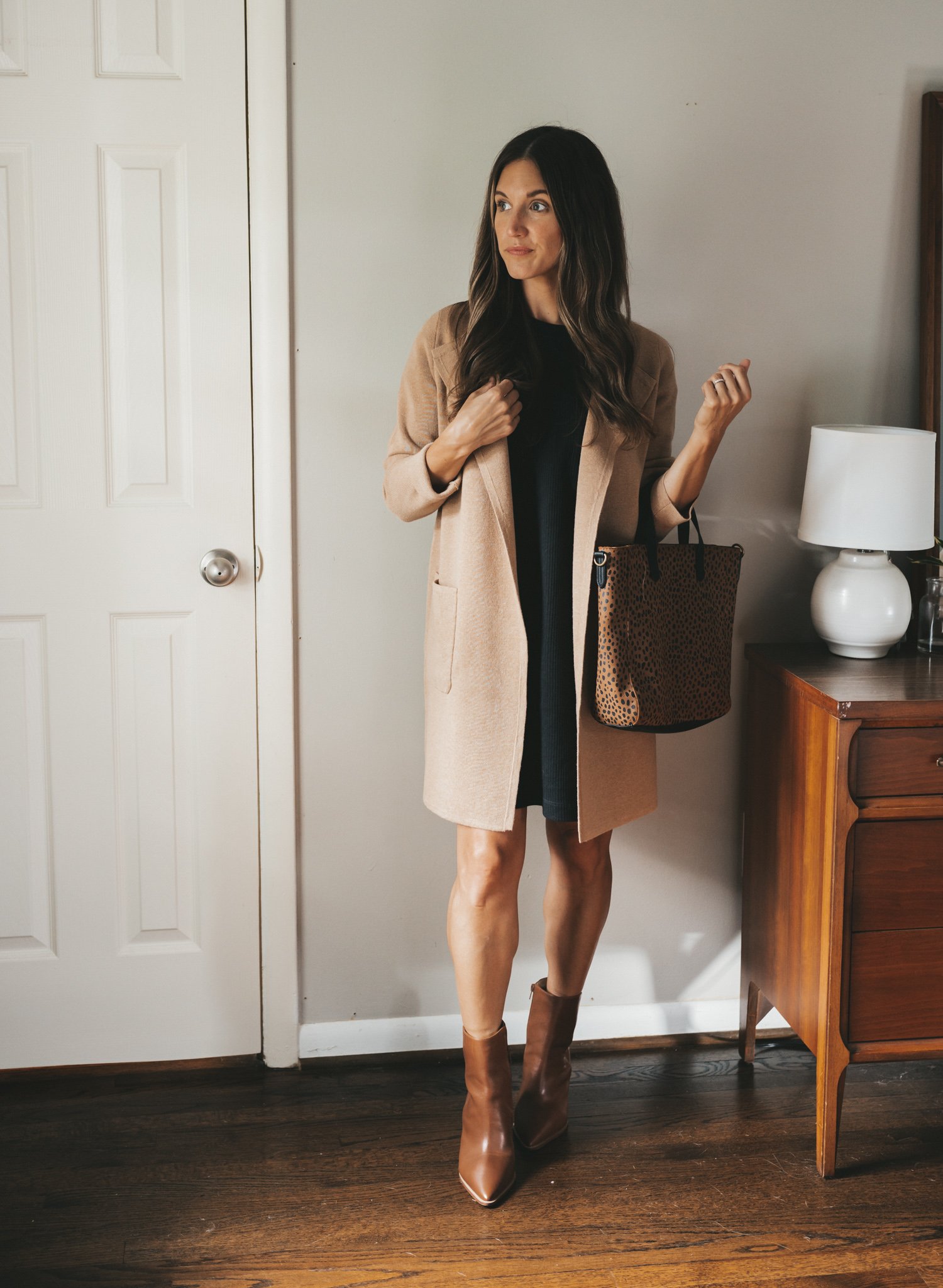ashley wearing a black t-shirt dress // tan long coatigan, cognac ankle boots, and a leopard print tote bag