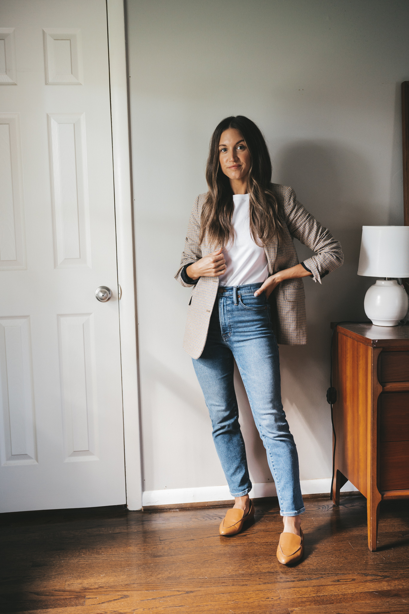 ashley wearing a plaid blazer over a white tee, medium wash denim, and cognac loafers