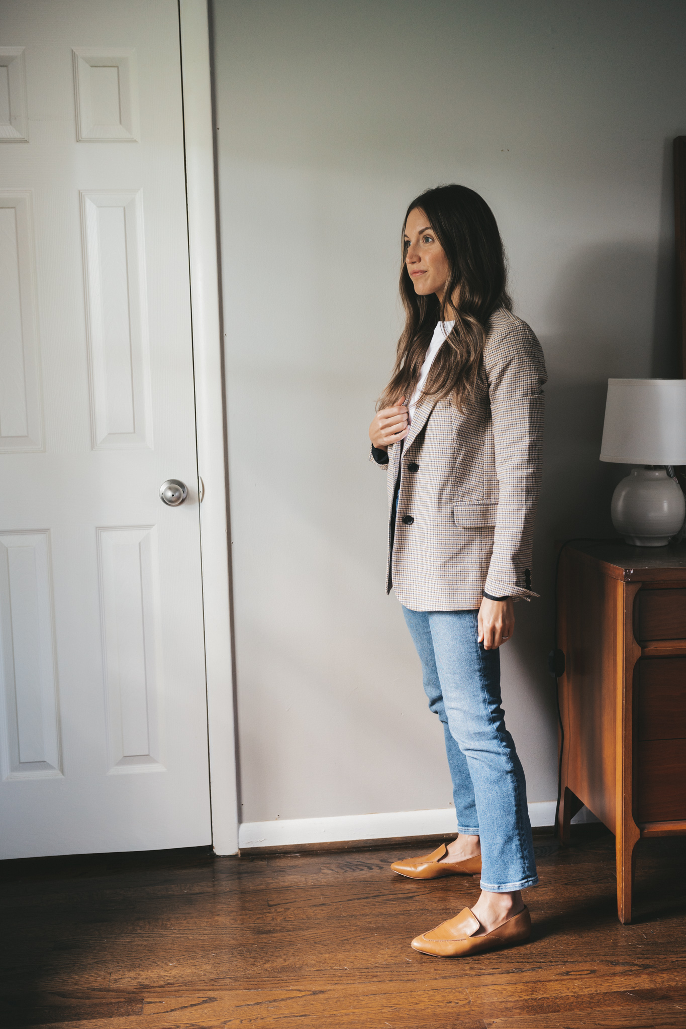 ashley wearing a plaid blazer over a white tee, medium wash denim, and cognac loafers