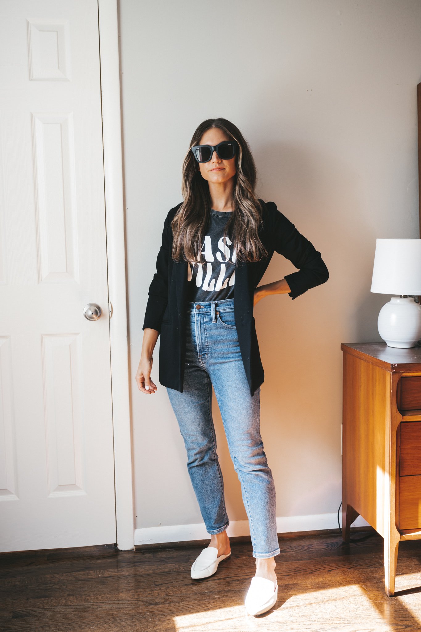 ashley wearing a black graphic tee that reads "Nashville" in white, a black blazer, medium wash denim, and white mules