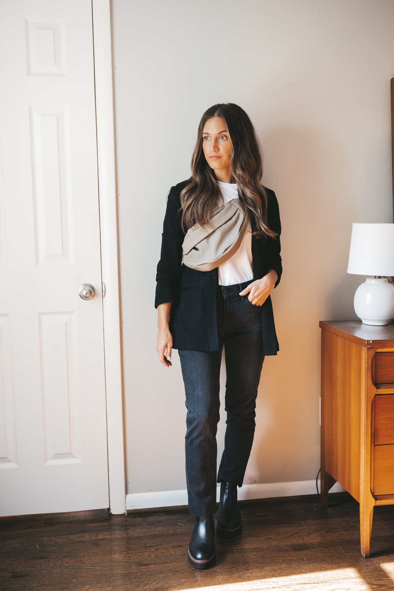 ashley wearing a white tee, black blazer, washed black boyfriend jeans, black Chelsea boots and an olive green belt bag