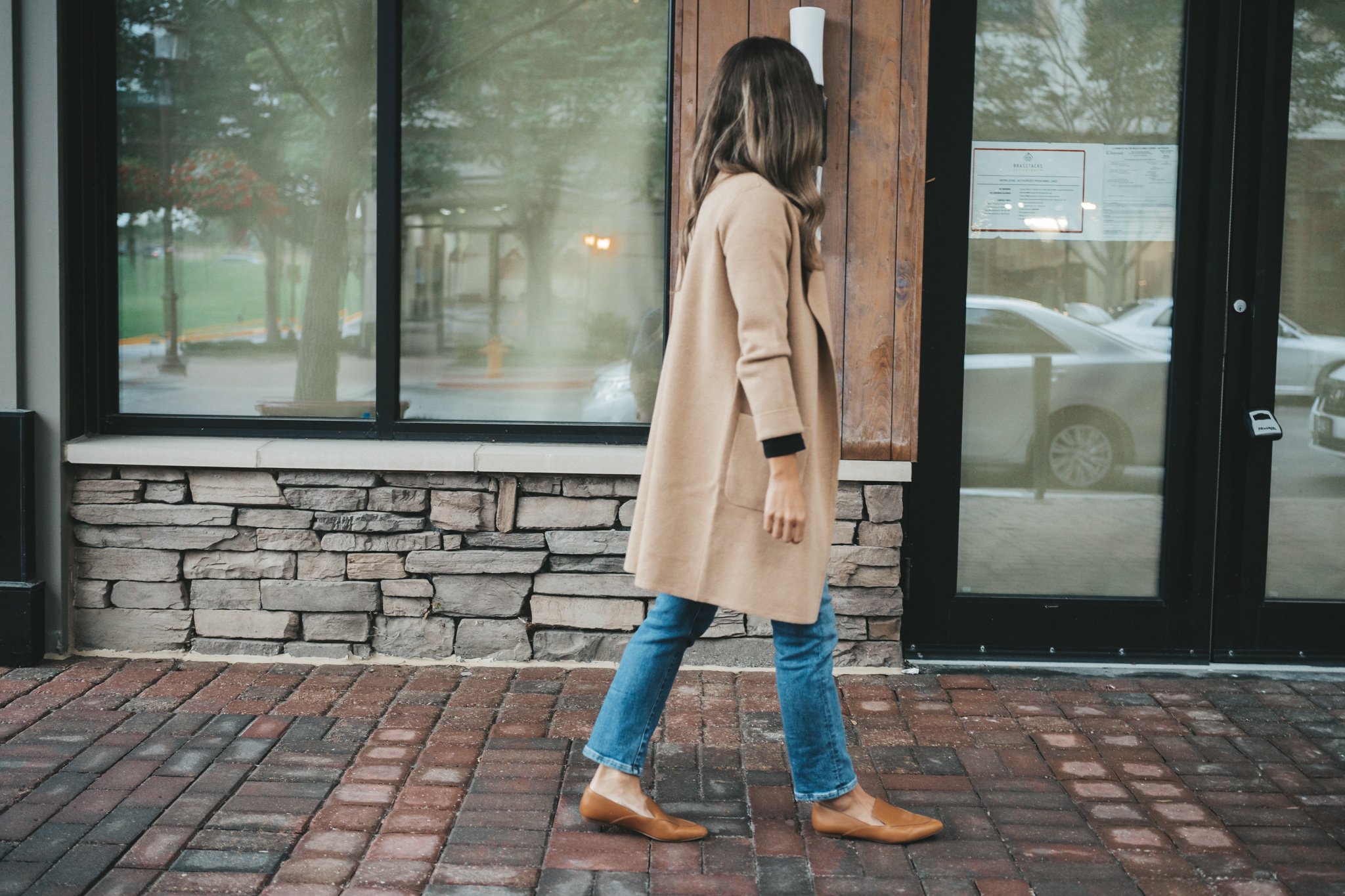 ashley walking down a sidewalk in front of a shop wearing a J.Crew Juliette Sweater Blazer, Mom Jeans, and Brown Loafers