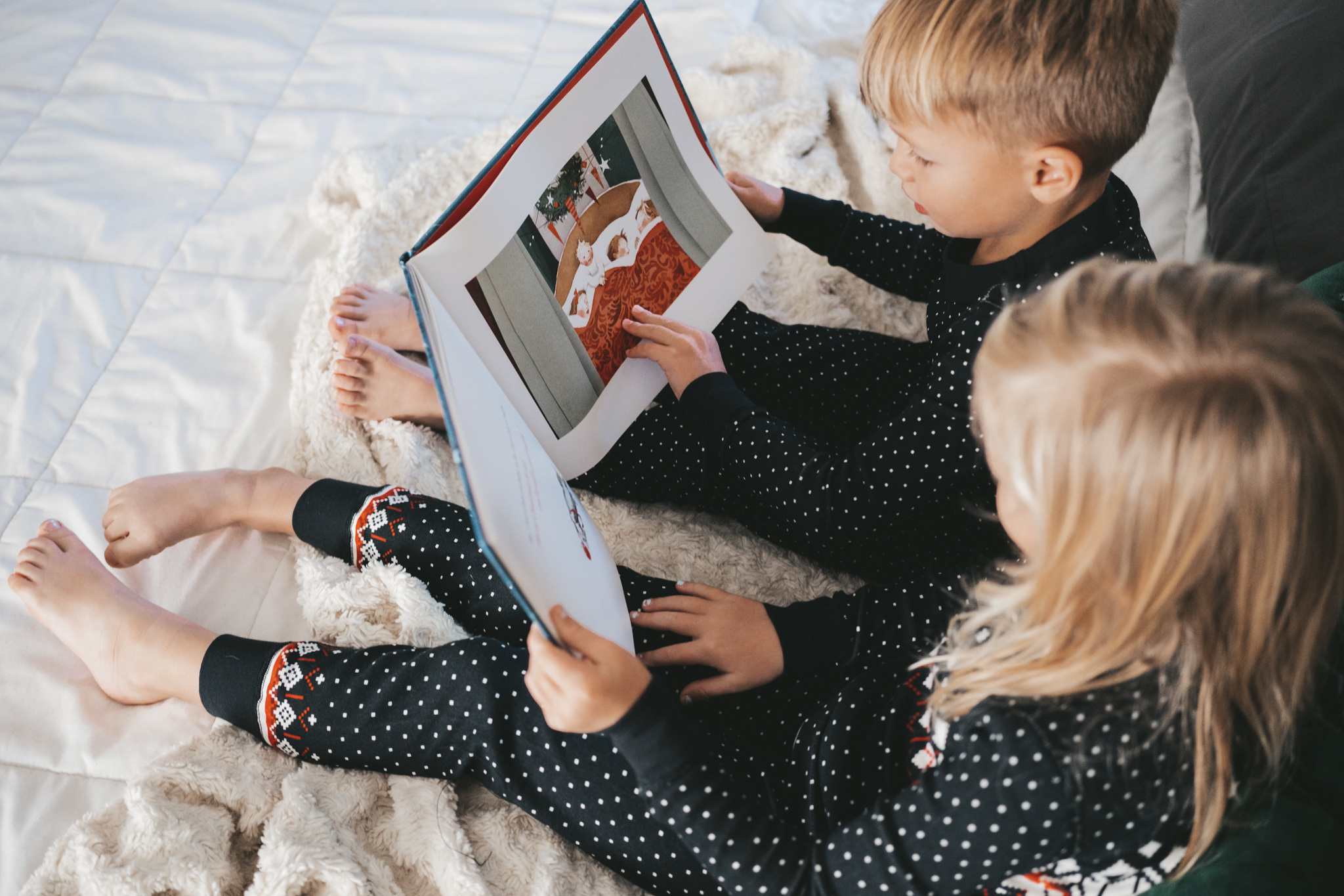 two kids in black, white and red holiday pajamas reading The Night Before Christmas