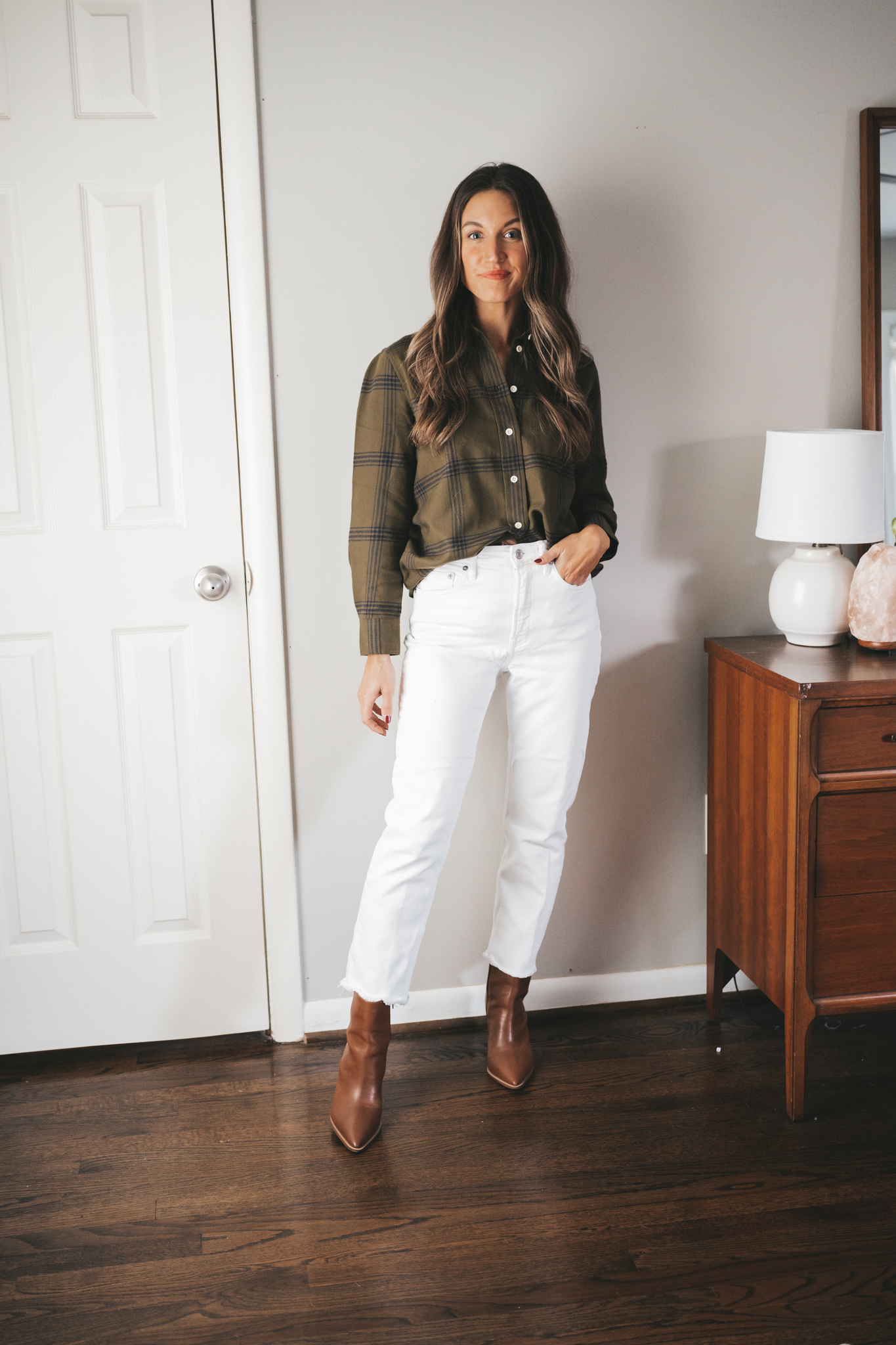ashley wearing a green and black plaid flannel, white straight denim, and cognac heeled booties