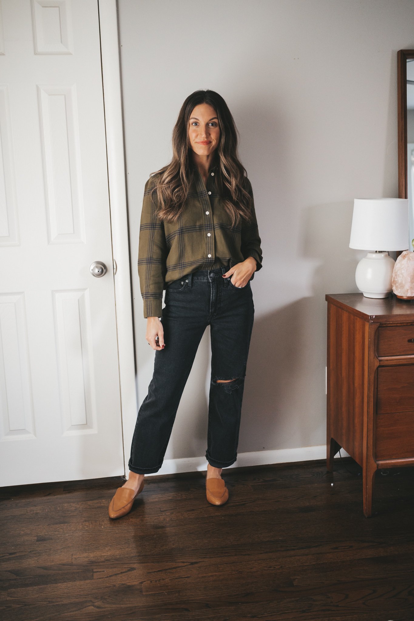 ashley wearing a green and black plaid flannel, black distressed straight denim, and cognac loafers
