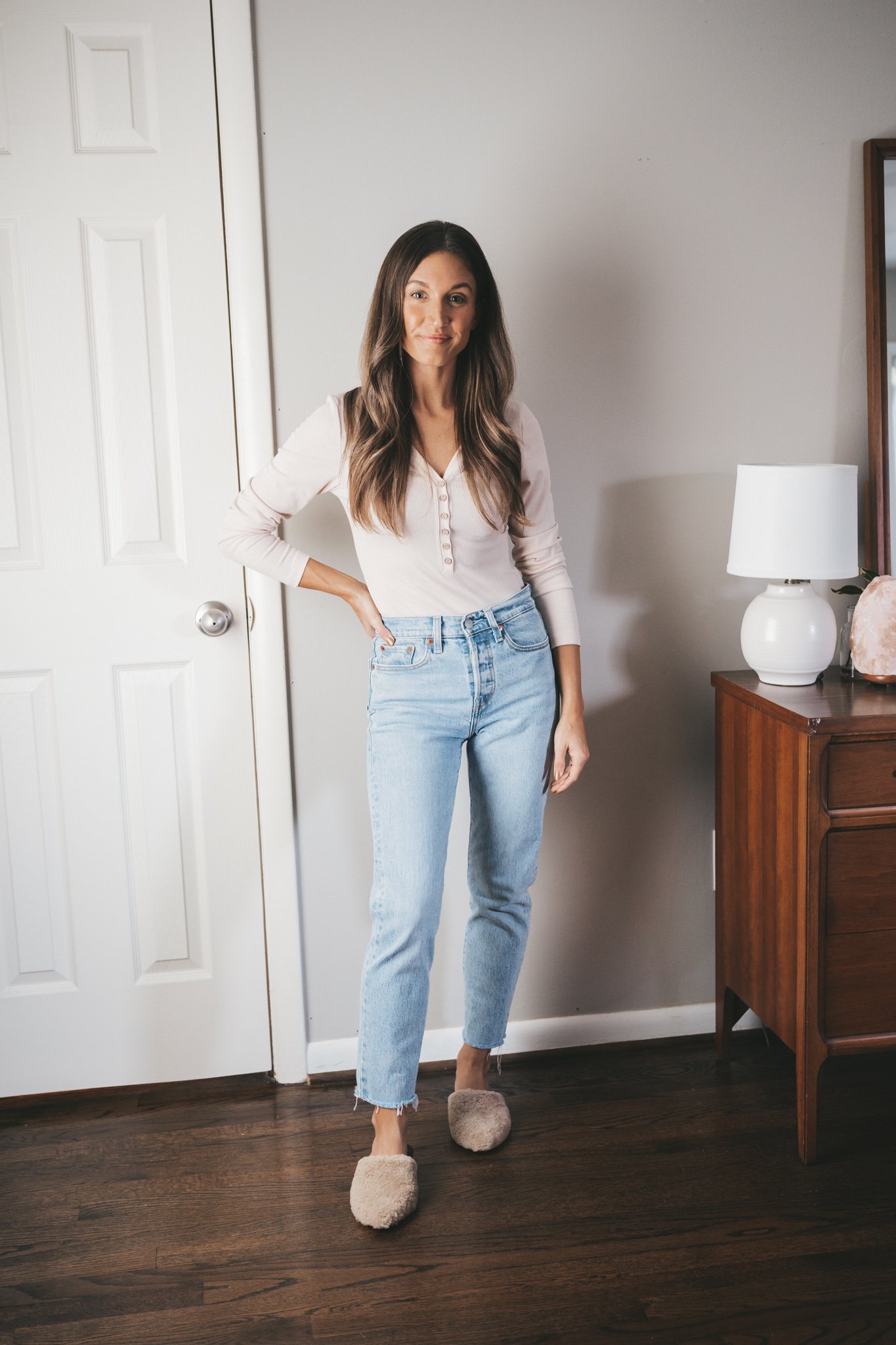 ashley wearing an ivory henley, light wash mom jeans, and tan shearling mules