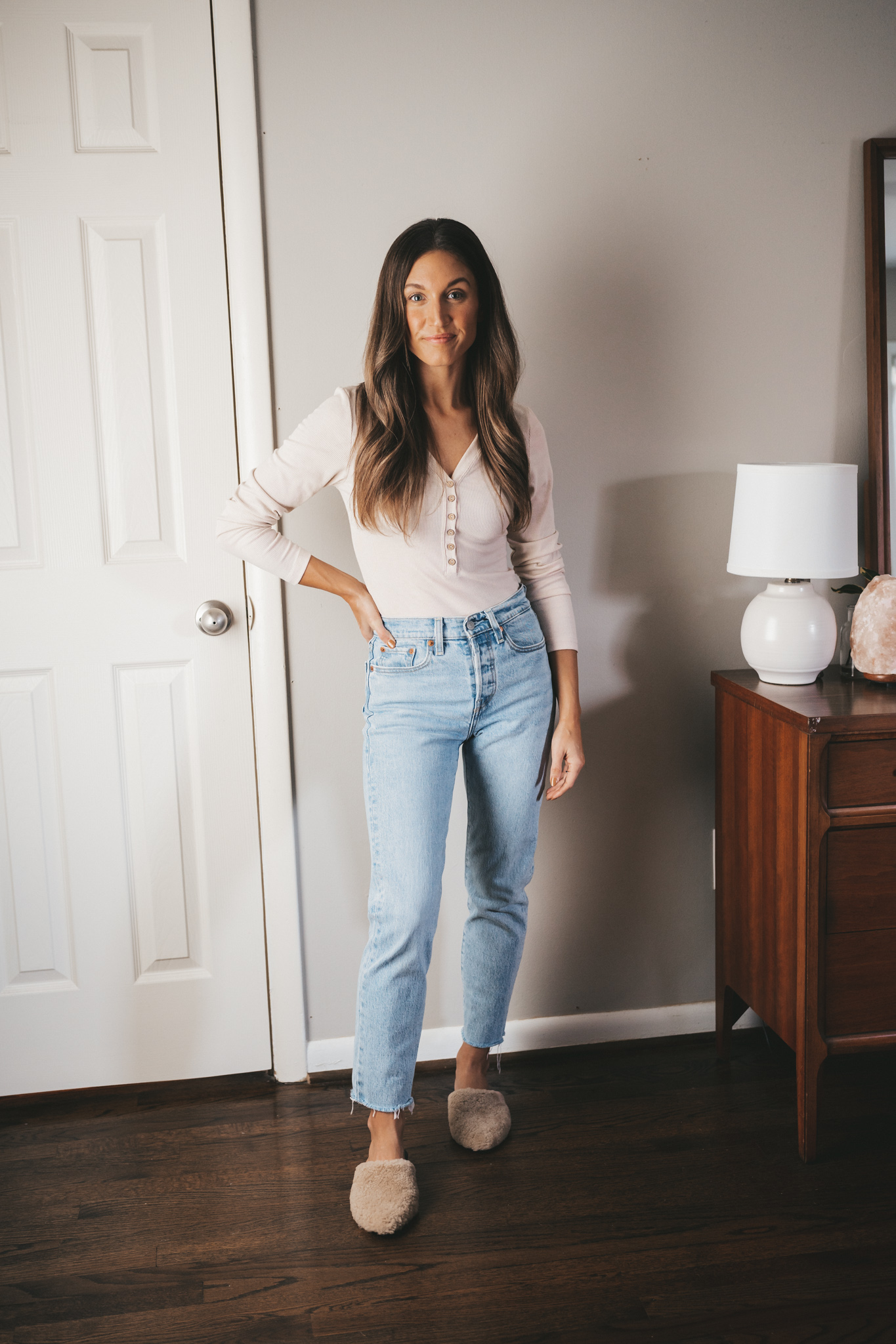 ashley wearing an ivory henley, light wash mom jeans, and tan shearling mules