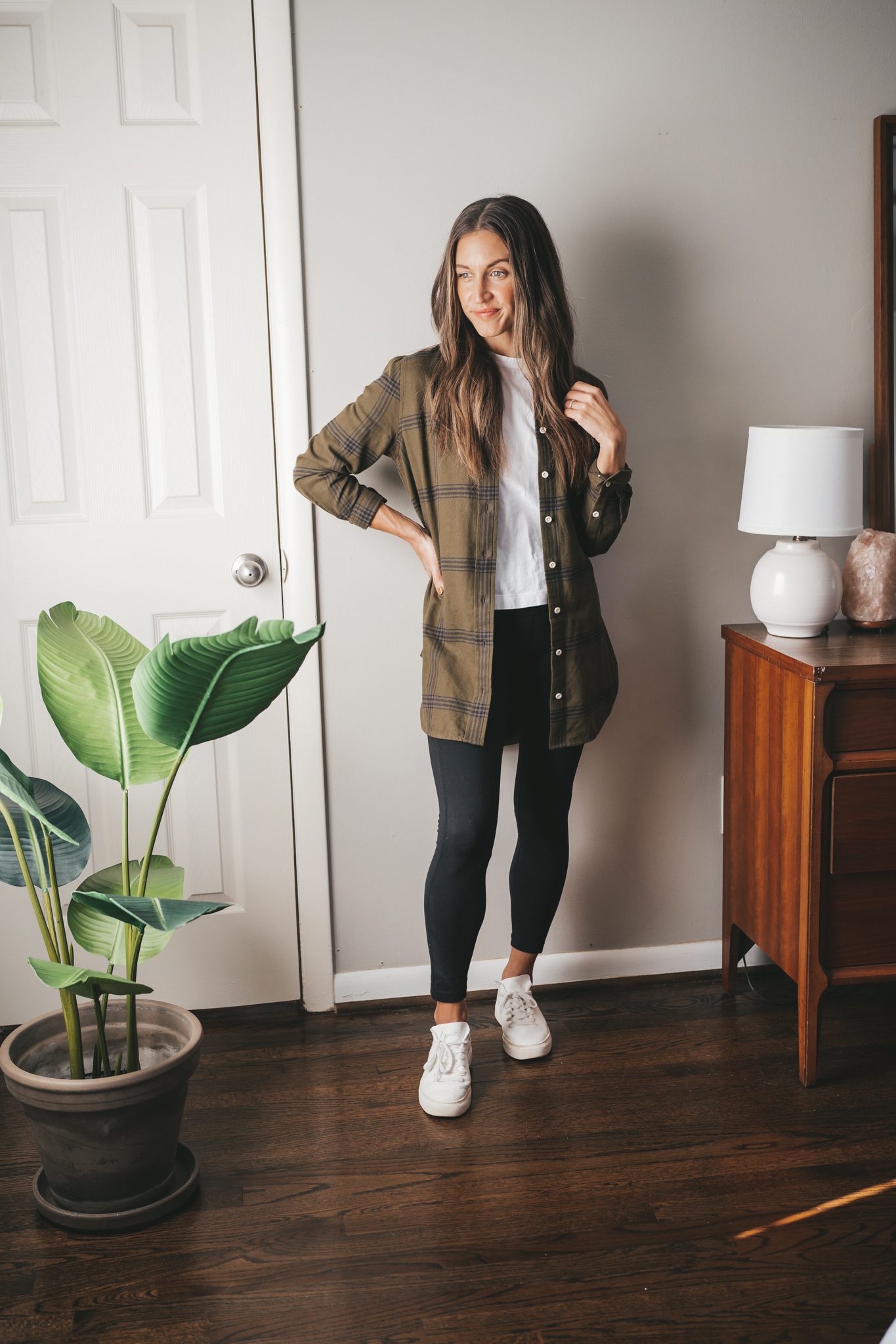 fall outfit idea with a green and black plaid flannel worn unbuttoned with a white tee, black leggings, and white sneakers