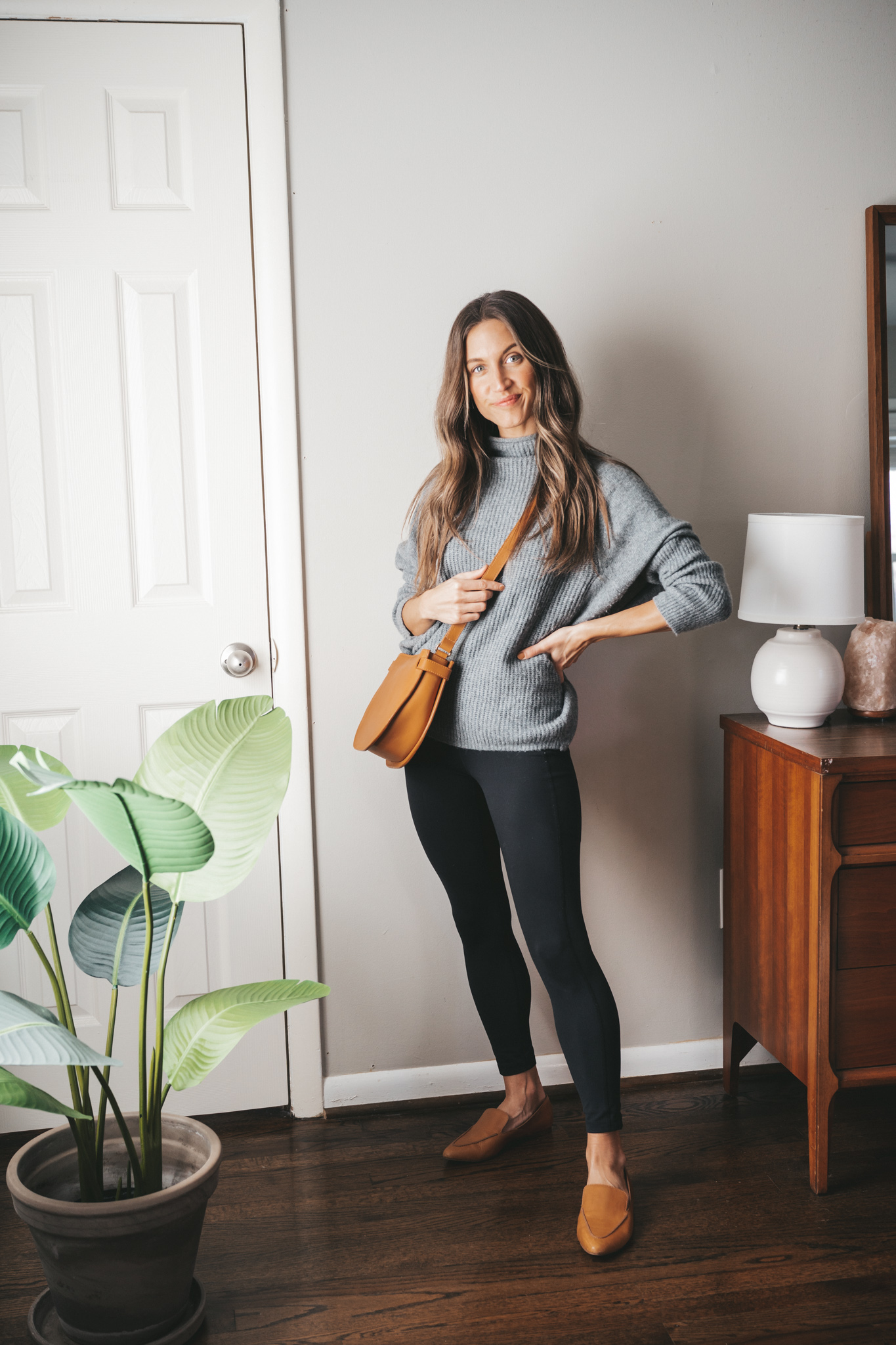 leggings outfit idea with a gray oversized sweater, black leggings, cognac loafers and a cognac crossbody bag