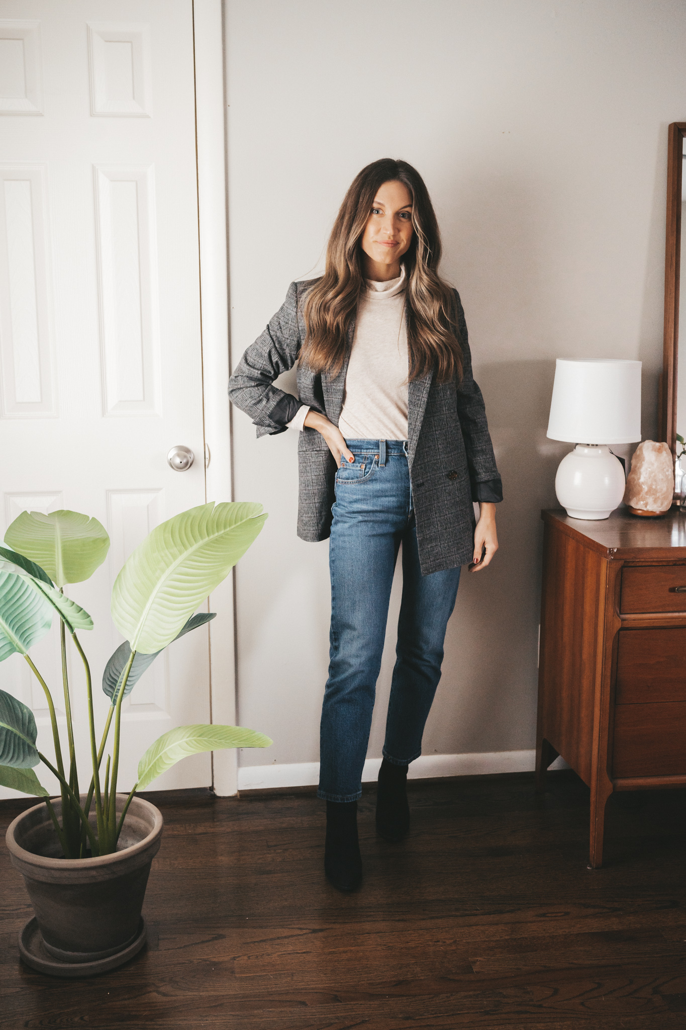 ashley showing one way to style a turtleneck with an oversized plaid blazer, mid-wash straight denim, and black ankle boots