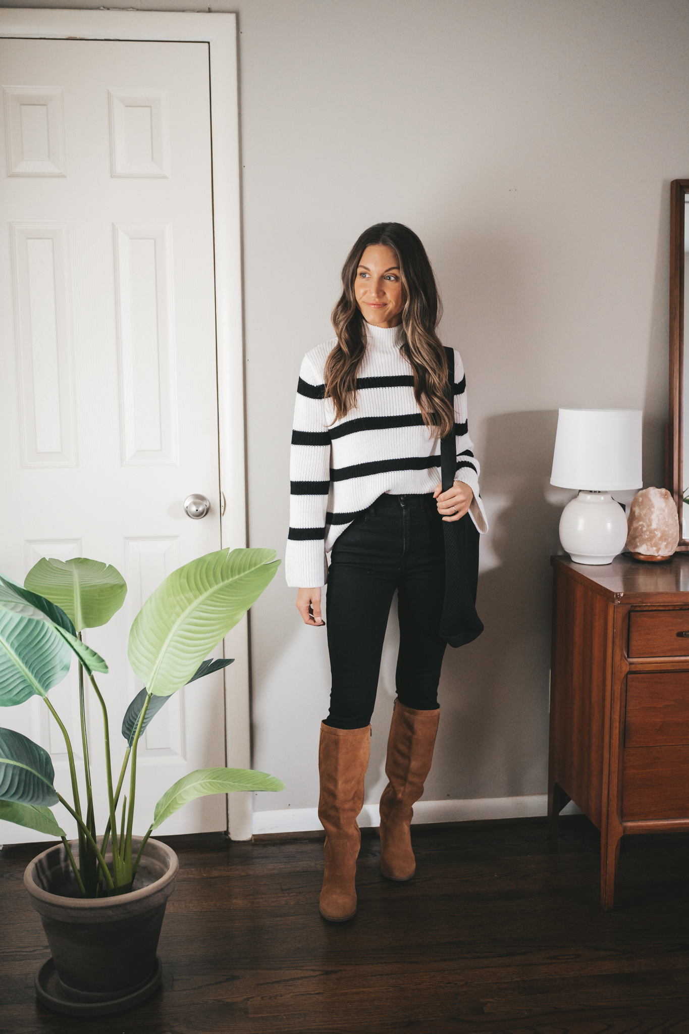 winter outfit idea with a striped sweater, black skinny jeans, brown suede knee high boots, and a black tote bag