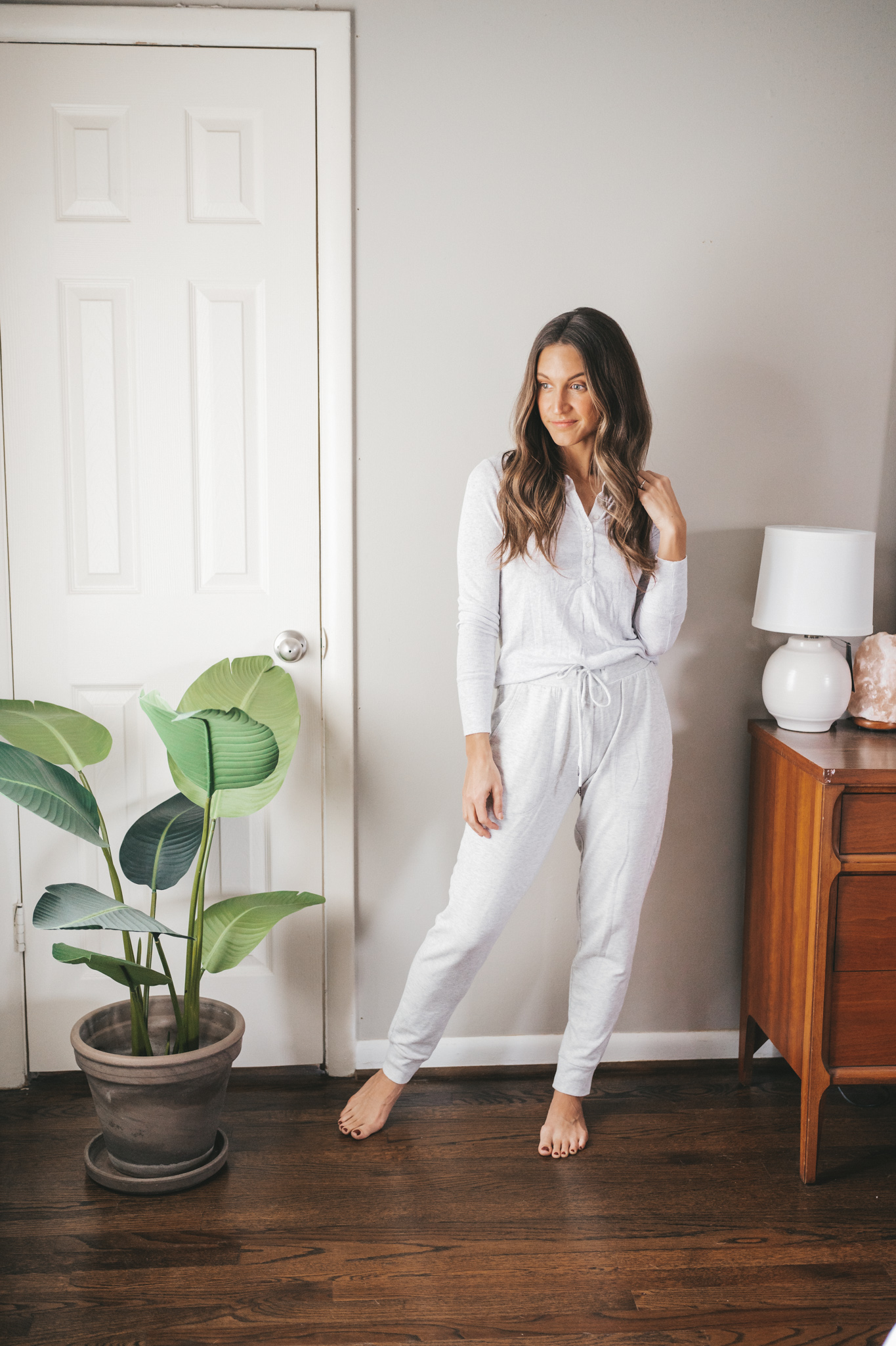 ashley wearing a Christmas morning outfit idea with a light gray henley top and light gray sweatpants