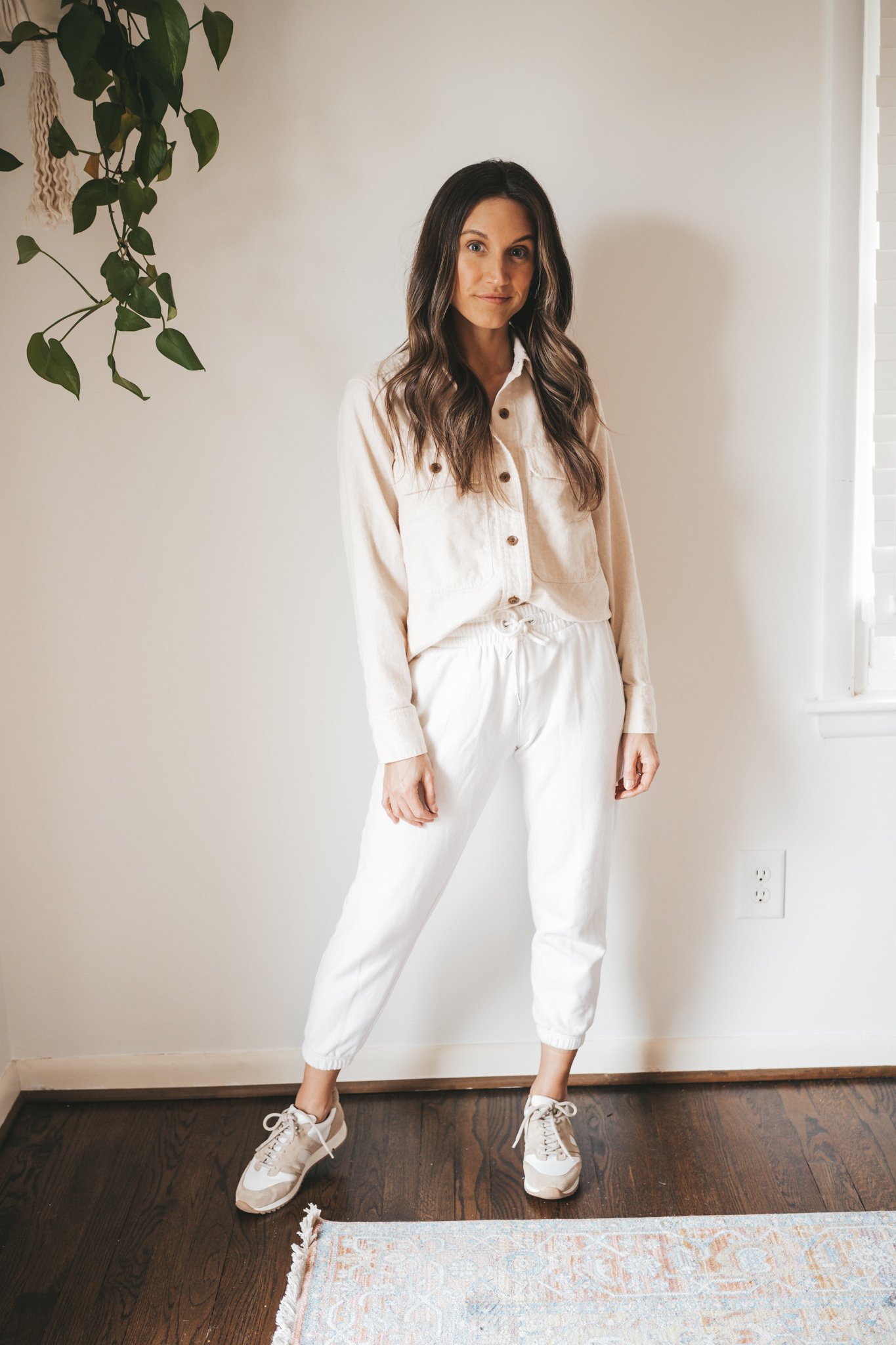 ashley wearing a cream colored flannel, white joggers, and white and tan sneakers