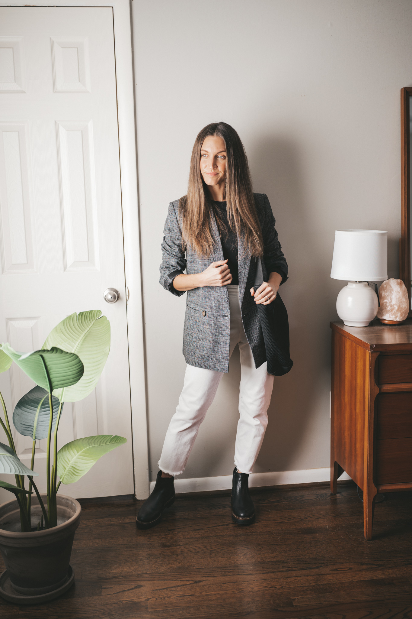 winter outfit idea with a black long sleeved tee, gray plaid blazer, white straight denim, black lug sole chelsea boots, and a black tote bag