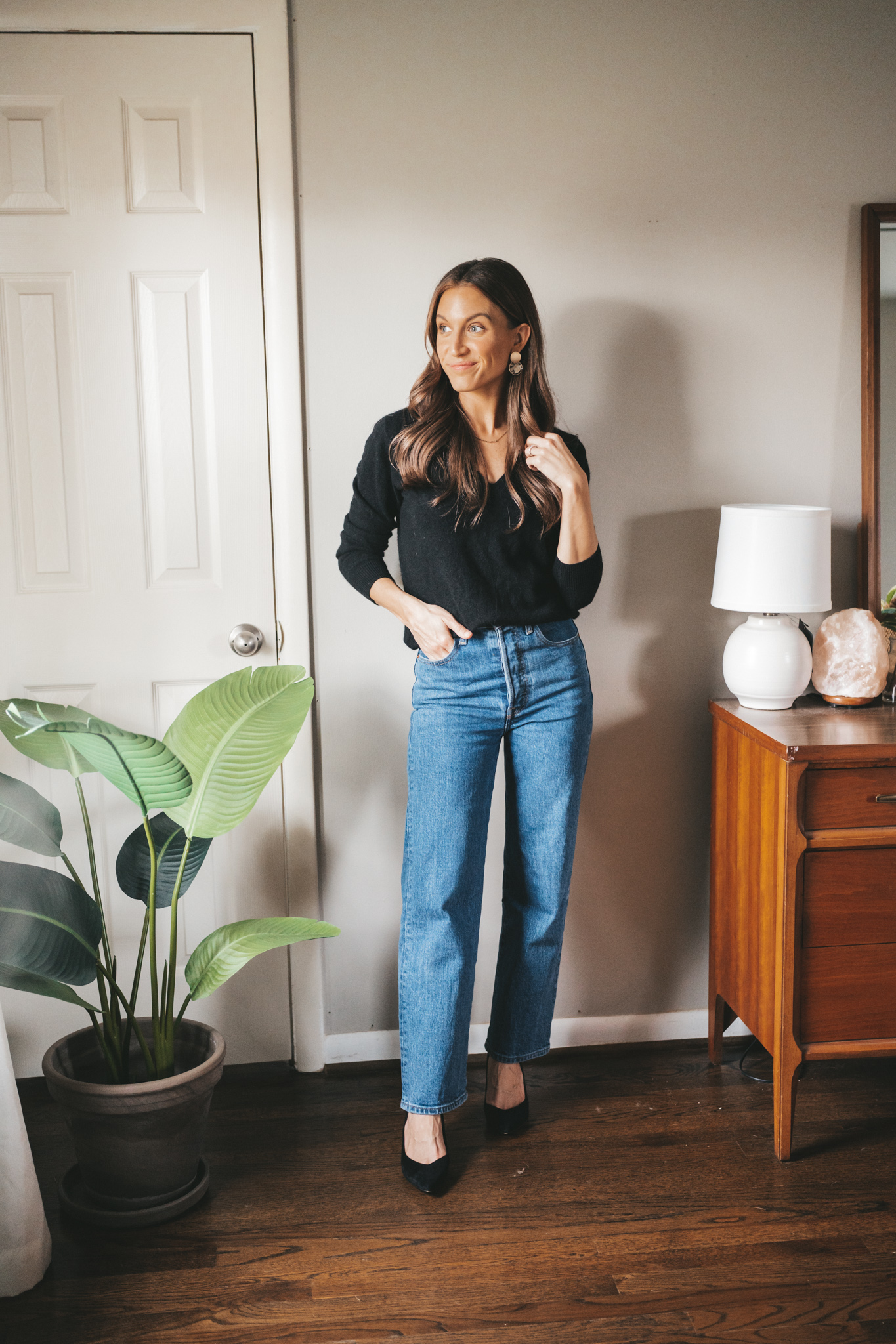 winter outfit idea with a black v-neck cashmere sweater, mid-wash straight leg denim, and black block heels