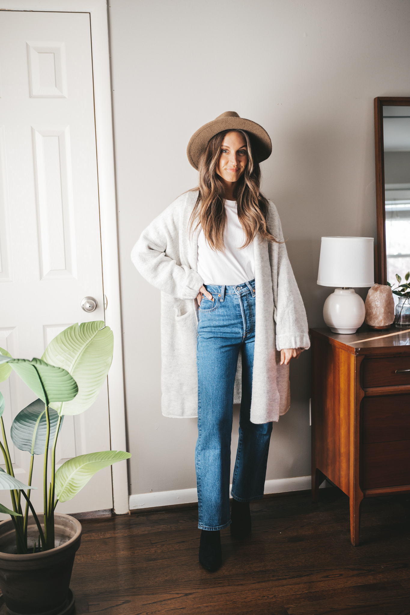 winter essential straight leg denim worn with a white tee, gray sweater coat, black ankle boots and a taupe felt fedora