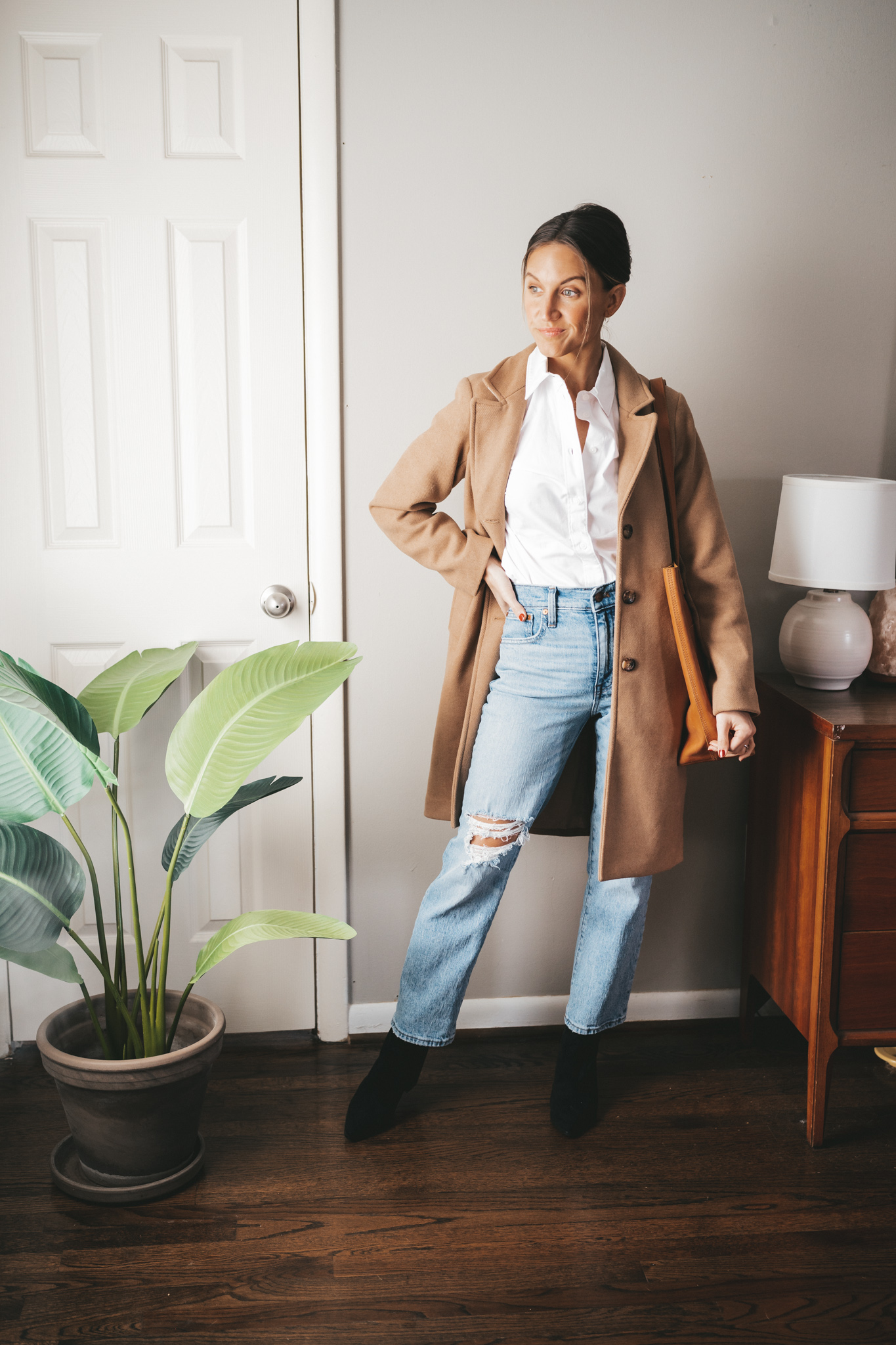 winter essential camel coat with a white button, light wash distressed straight denim, black ankle boots, and a cognac tote bag