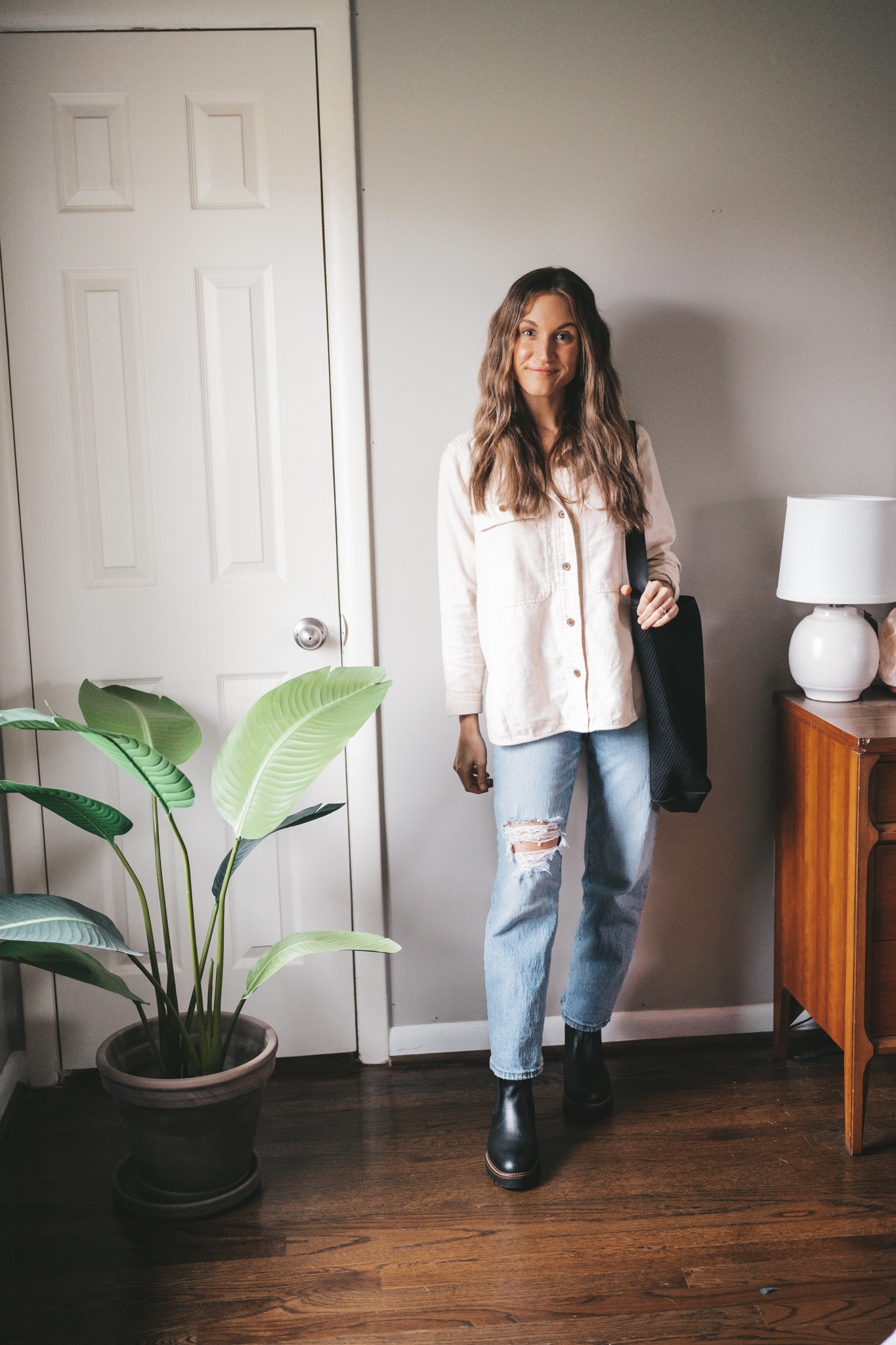 winter outfit idea with an ivory flannel, light wash distressed straight jeans, black lug-sole chelsea boots, and a black mesh tote bag