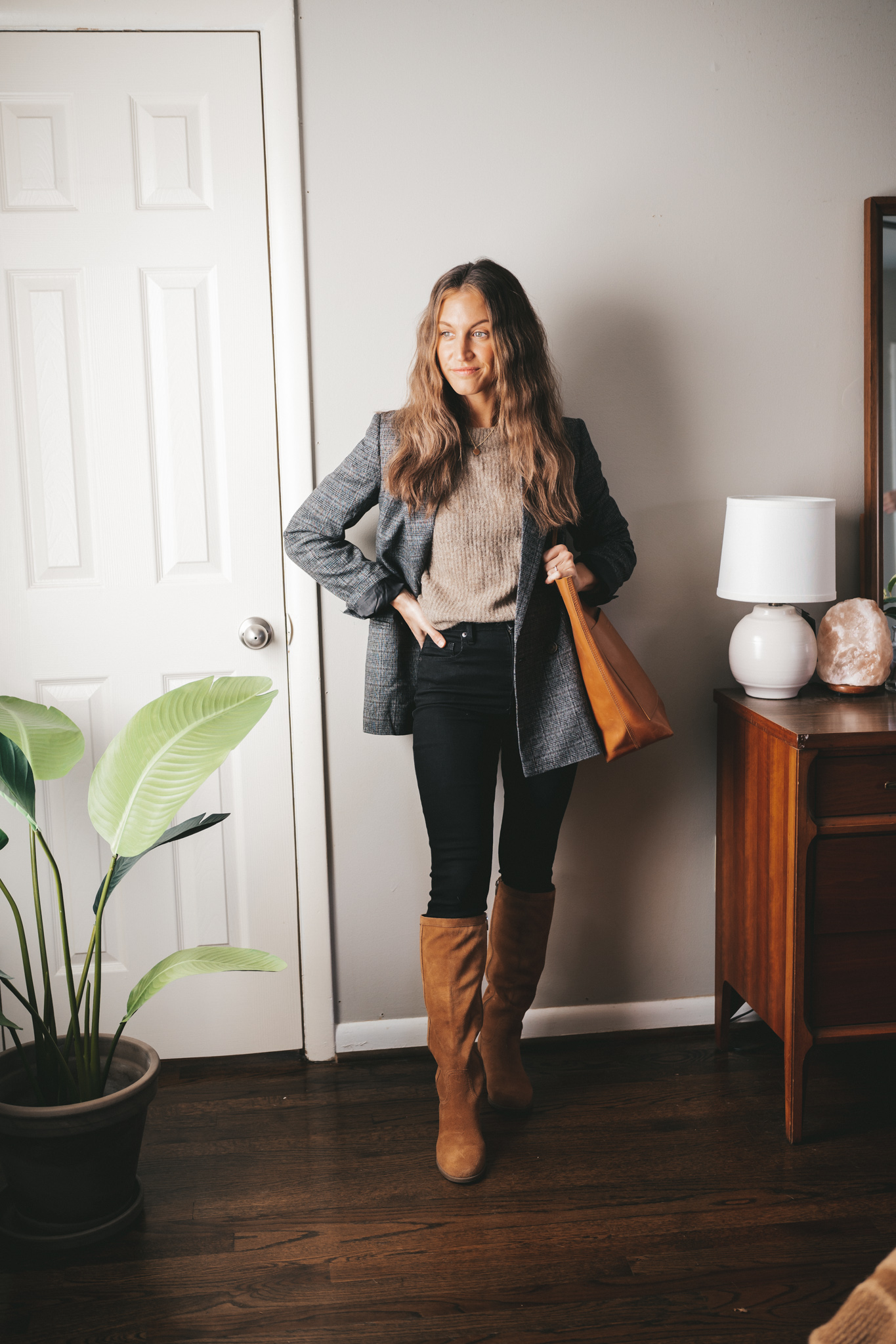 winter outfit idea with a taupe sweater, gray plaid blazer, black skinny jeans, suede cognac high knee boots, and a cognac tote bag