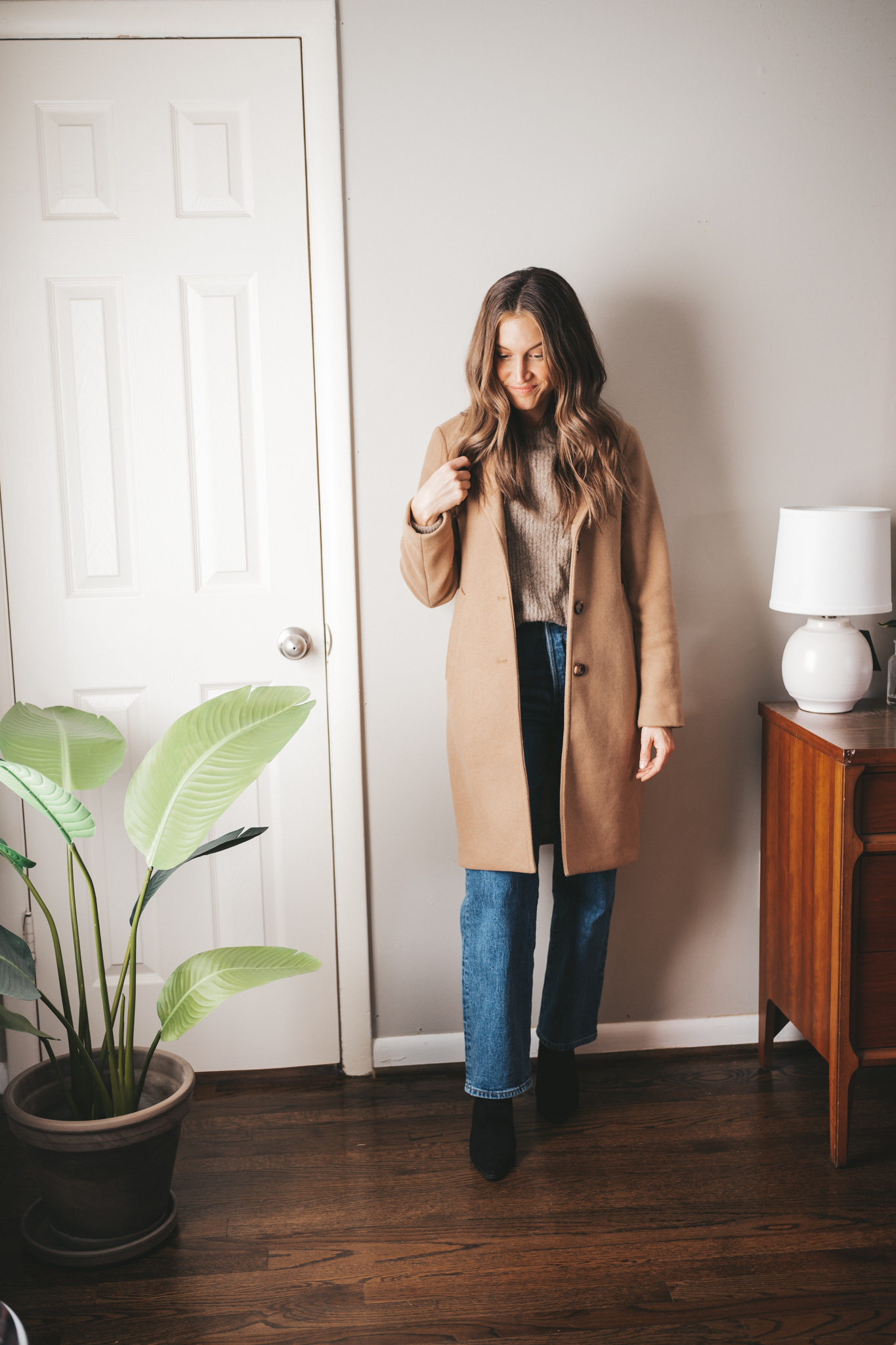 how to style a camel coat with a sweater, straight leg denim, and heeled ankle boots