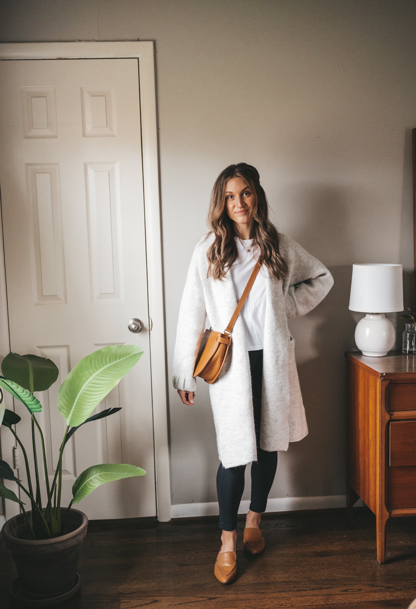 winter capsule wardrobe outfit idea with a white tee, gray sweater coat, leggings, and cognac loafers