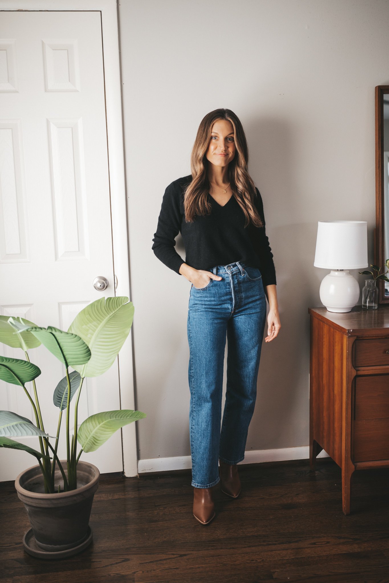winter capsule wardrobe black cashmere v-neck sweater worn with mid-wash straight denim and brown ankle boots