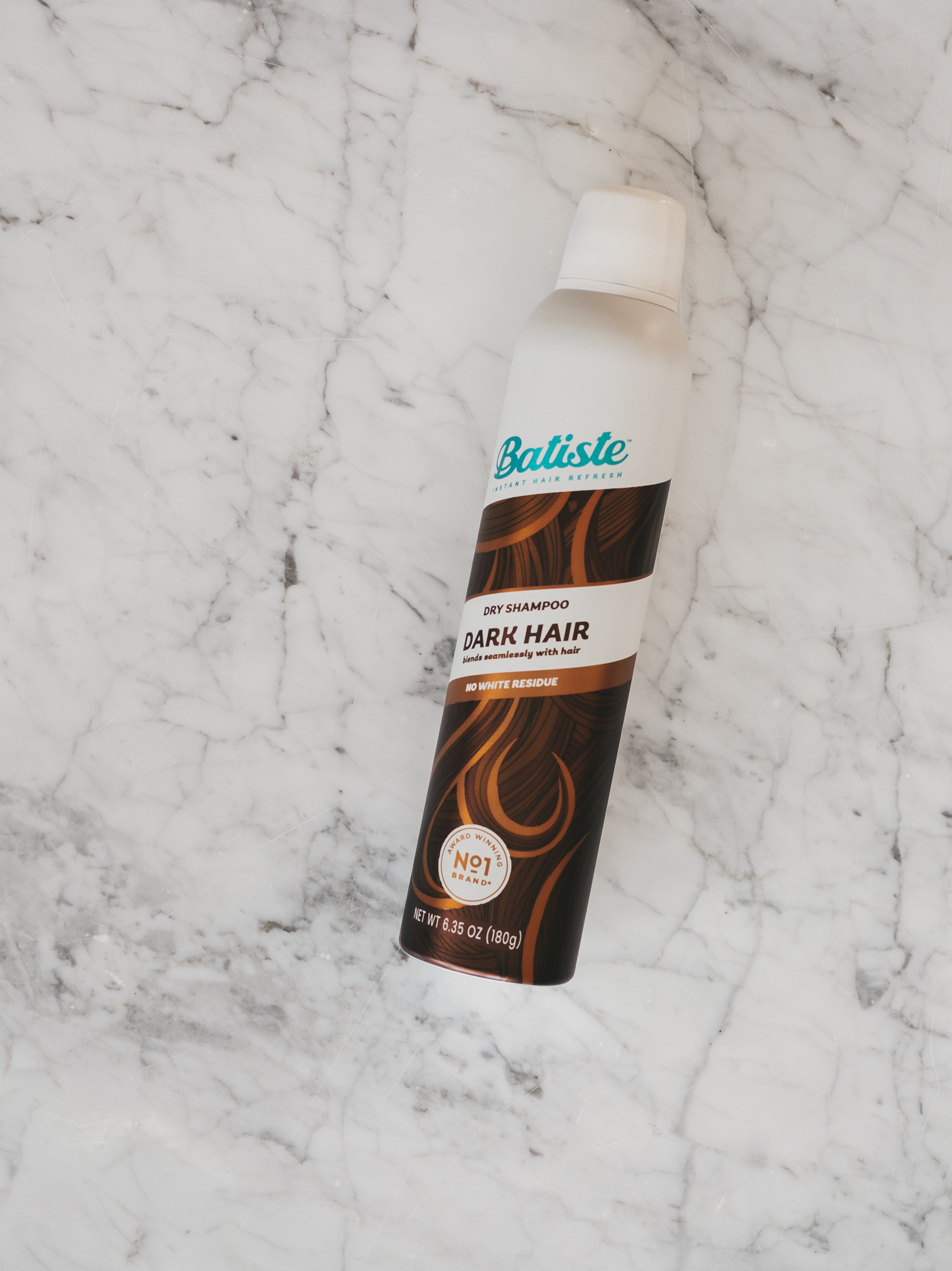 a white marble table with Batiste Dry Shampoo