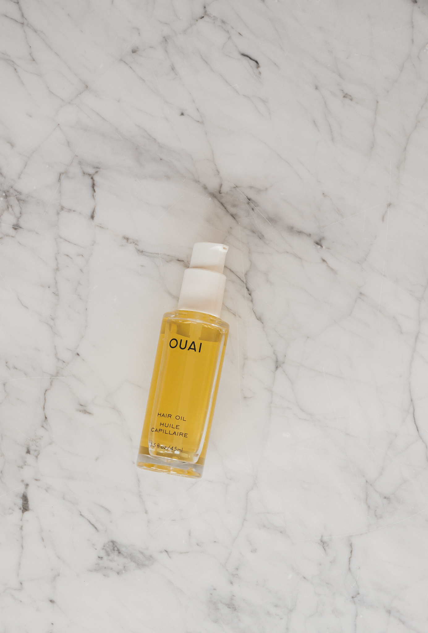 a white marble table with a bottle of Ouai Hair Oil