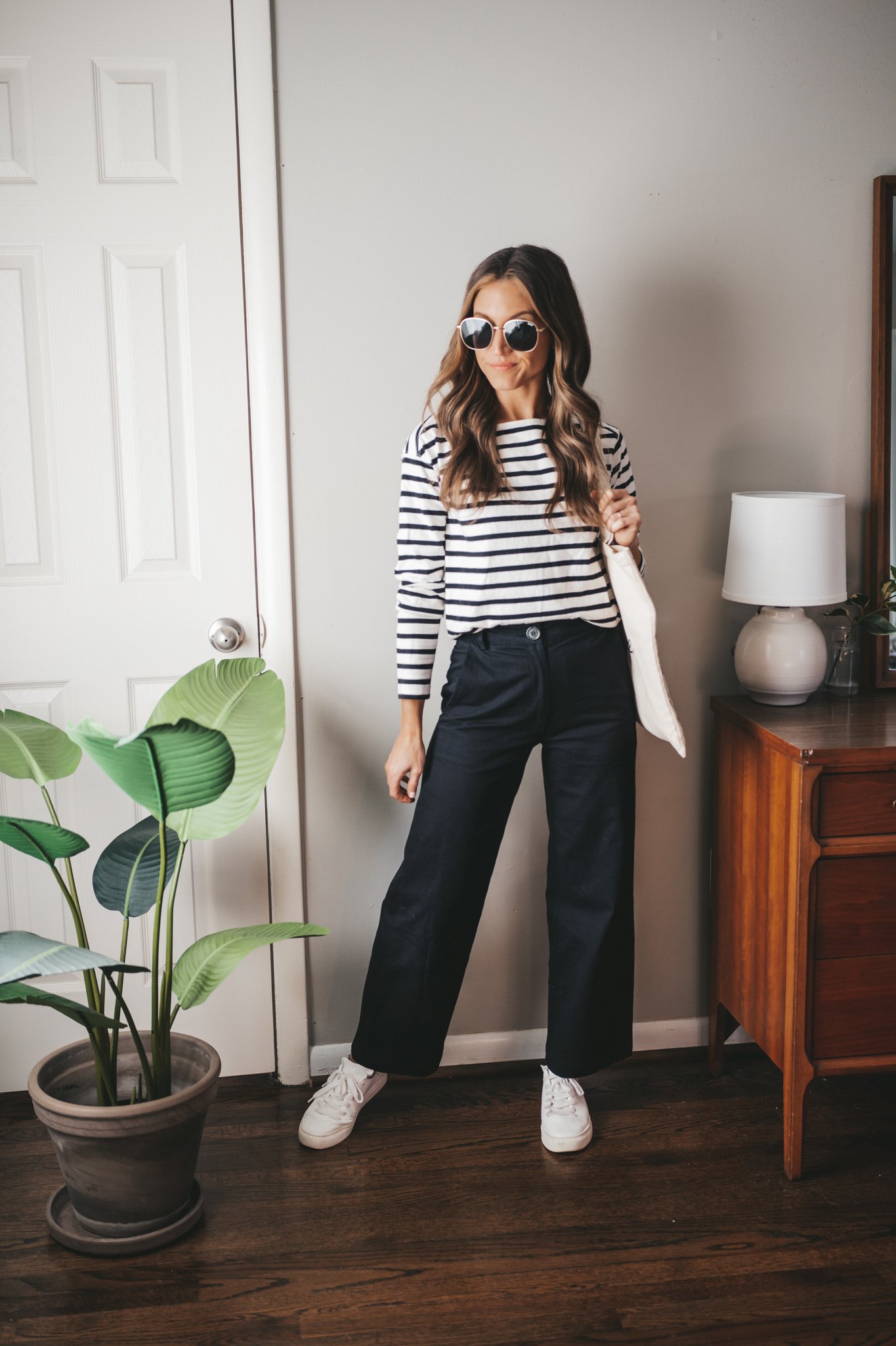 winter outfit idea with a striped top, black wide leg pants, and white sneakers