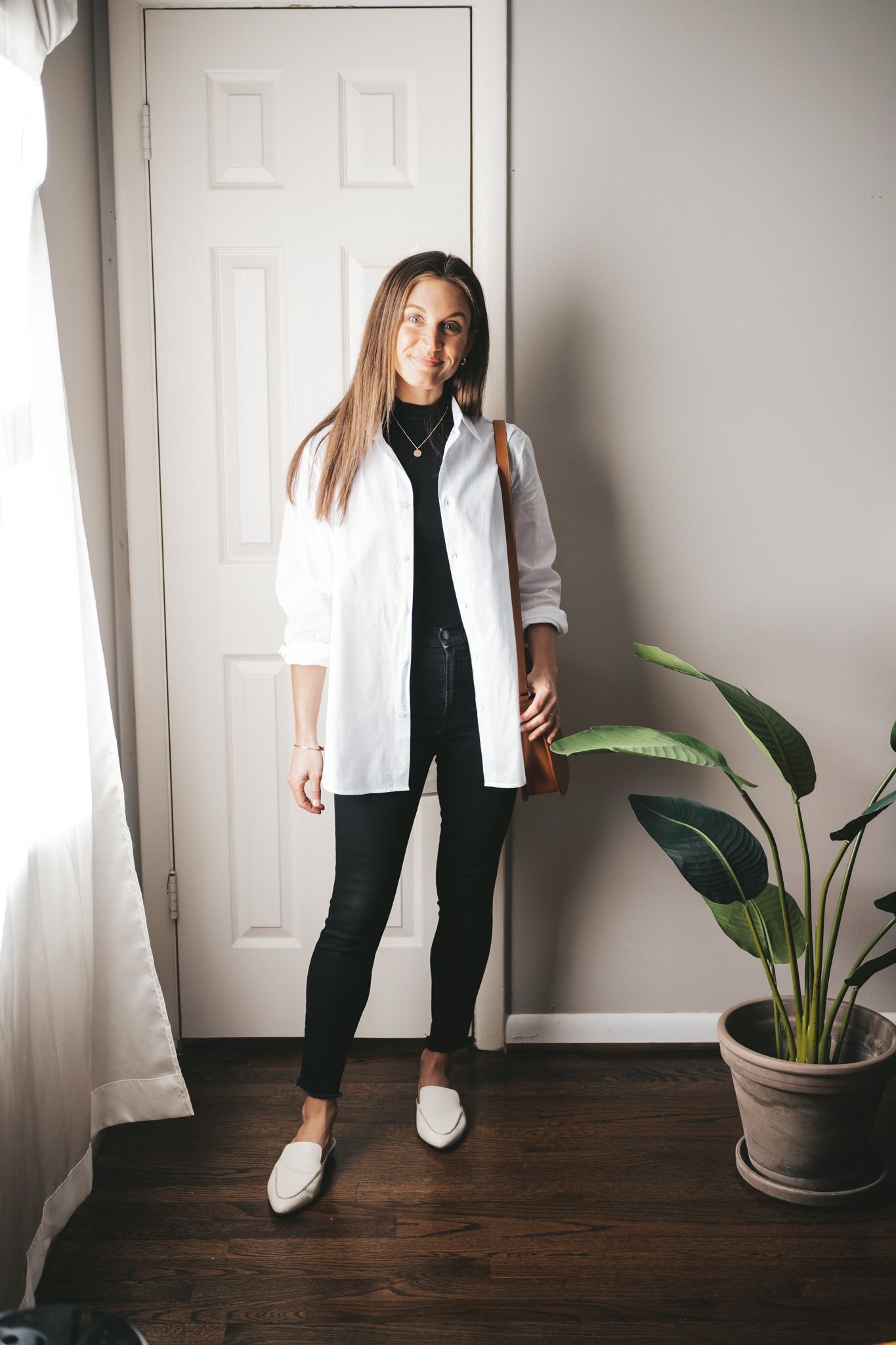 a winter mini capsule wardrobe outfit with a black mockneck tee, white button down, black skinny jeans, and white mules