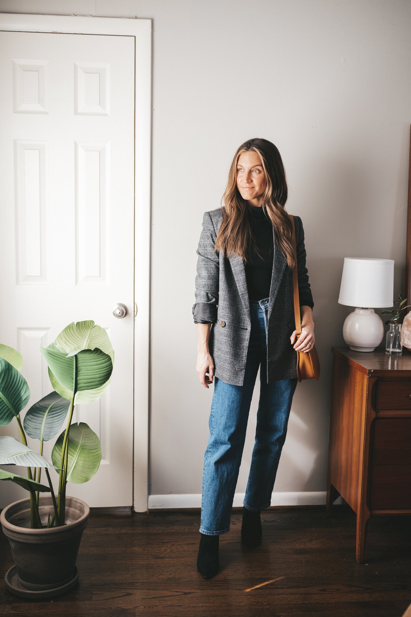blazer outfit with a black turtleneck, gray plaid blazer, straight high waisted denim, and black heeled ankle boots with a cognac crossbody bag