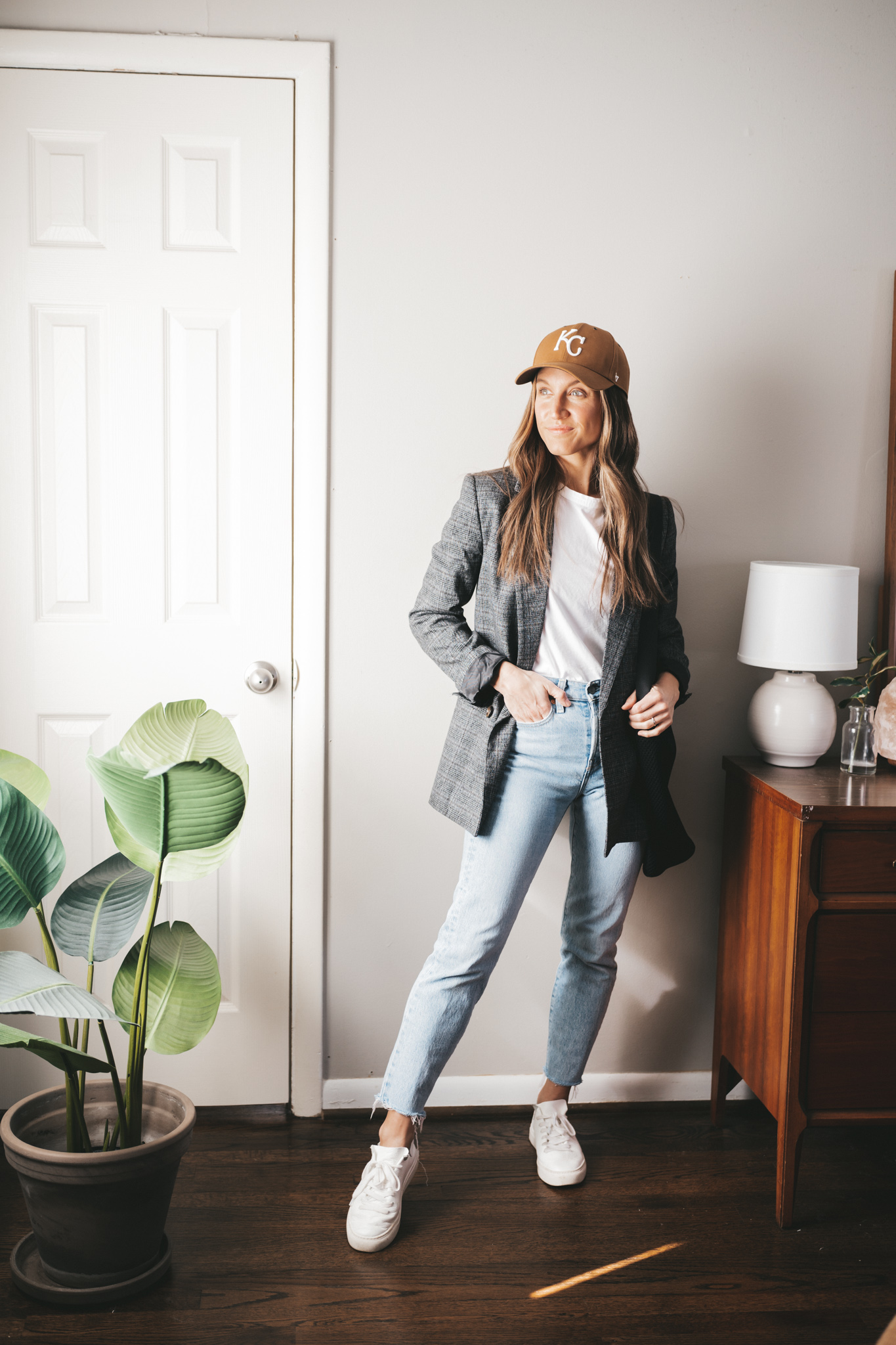 blazer outfit idea with a gray plaid blazer, white tee, light wash mom jeans, white sneakers, and a baseball cap