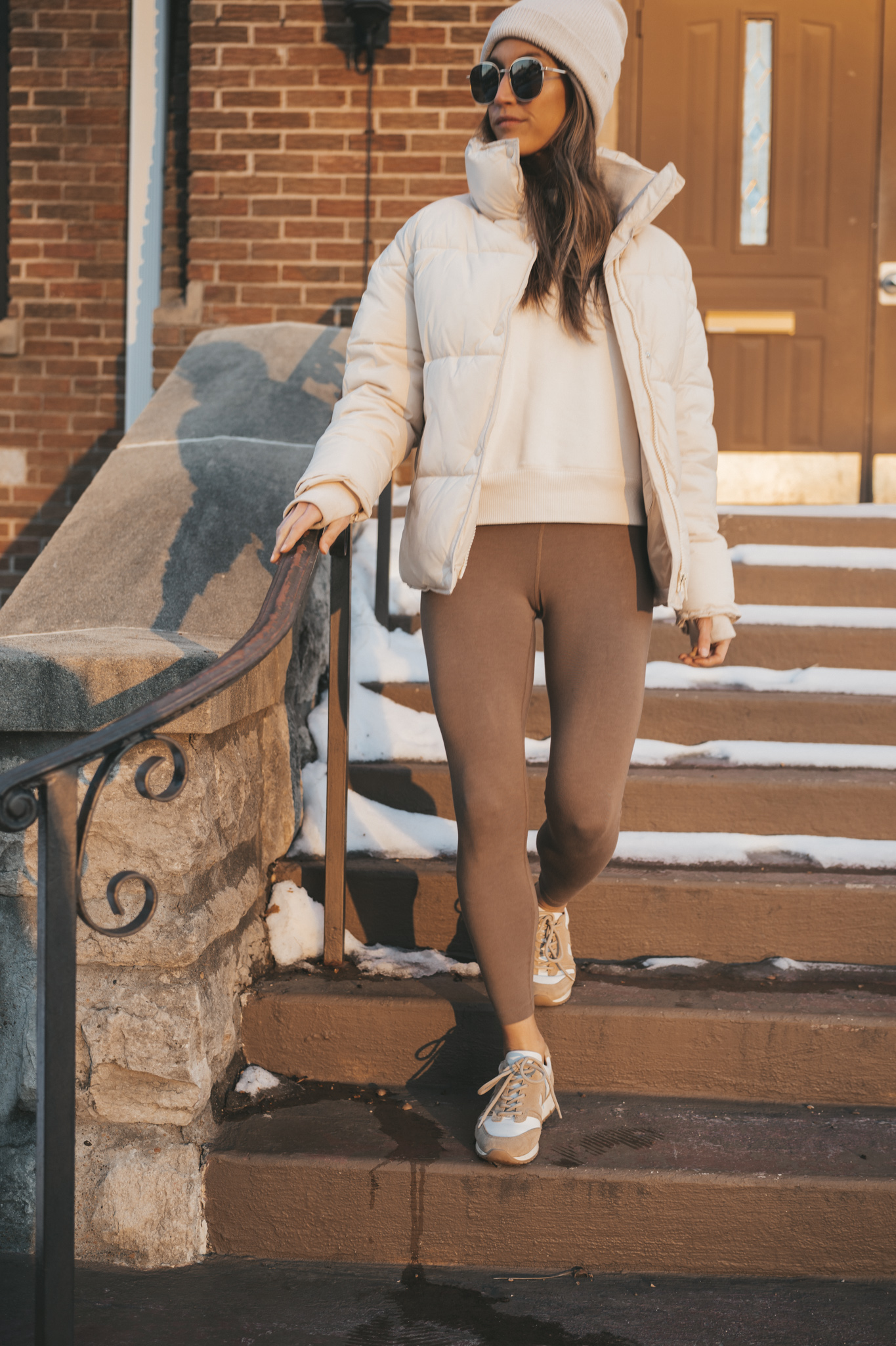 a tonal look with a white sweatshirt, taupe leggings, white puffer coat, tan and white sneakers, and a white beanie