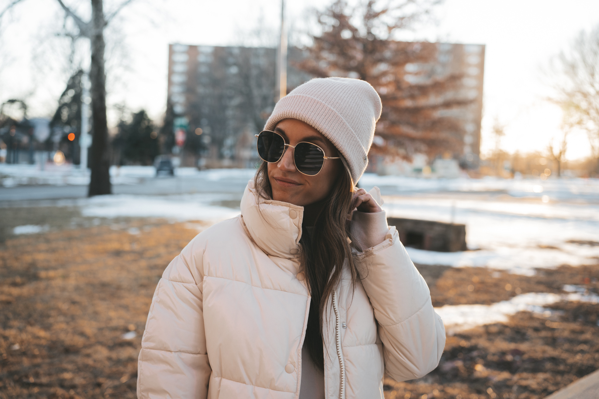 a tonal look with a white sweatshirt, taupe leggings, white puffer coat, tan and white sneakers, and a white beanie