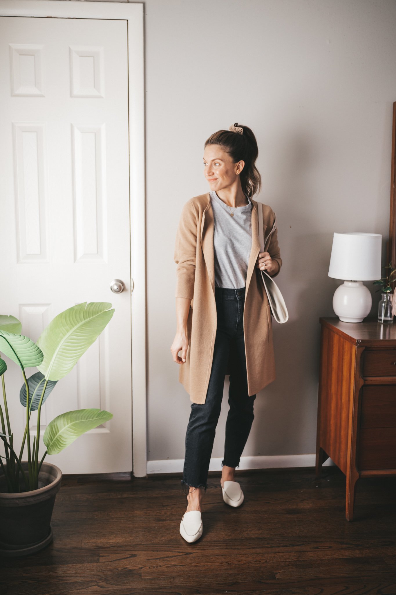 spring inspired outfit idea with a gray tee, long line sweater blazer, black denim, and white mules