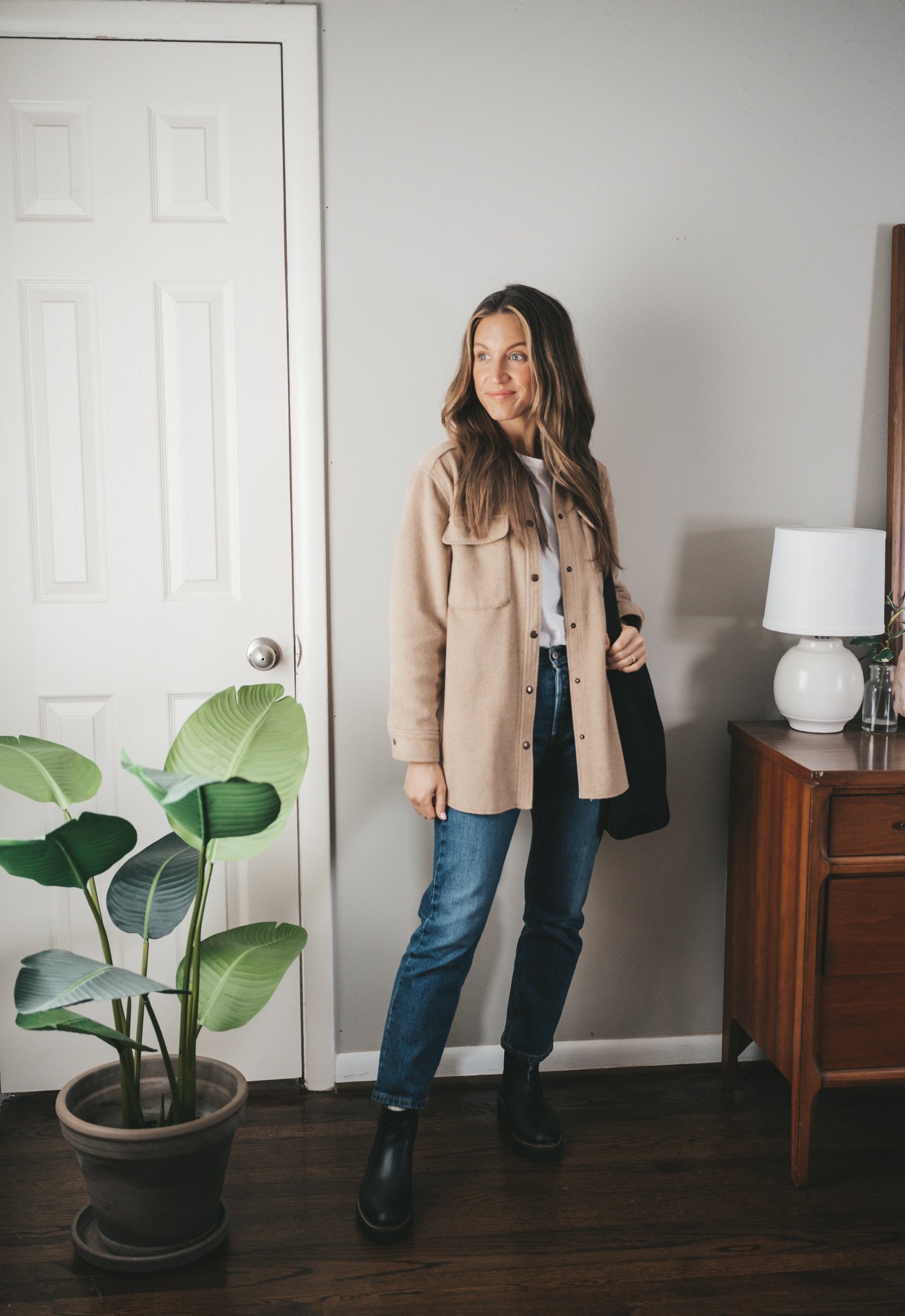 casual spring outfit idea with a white tee, tan shacket, dark wash straight denim, black lug sole boots, and a black tote bag