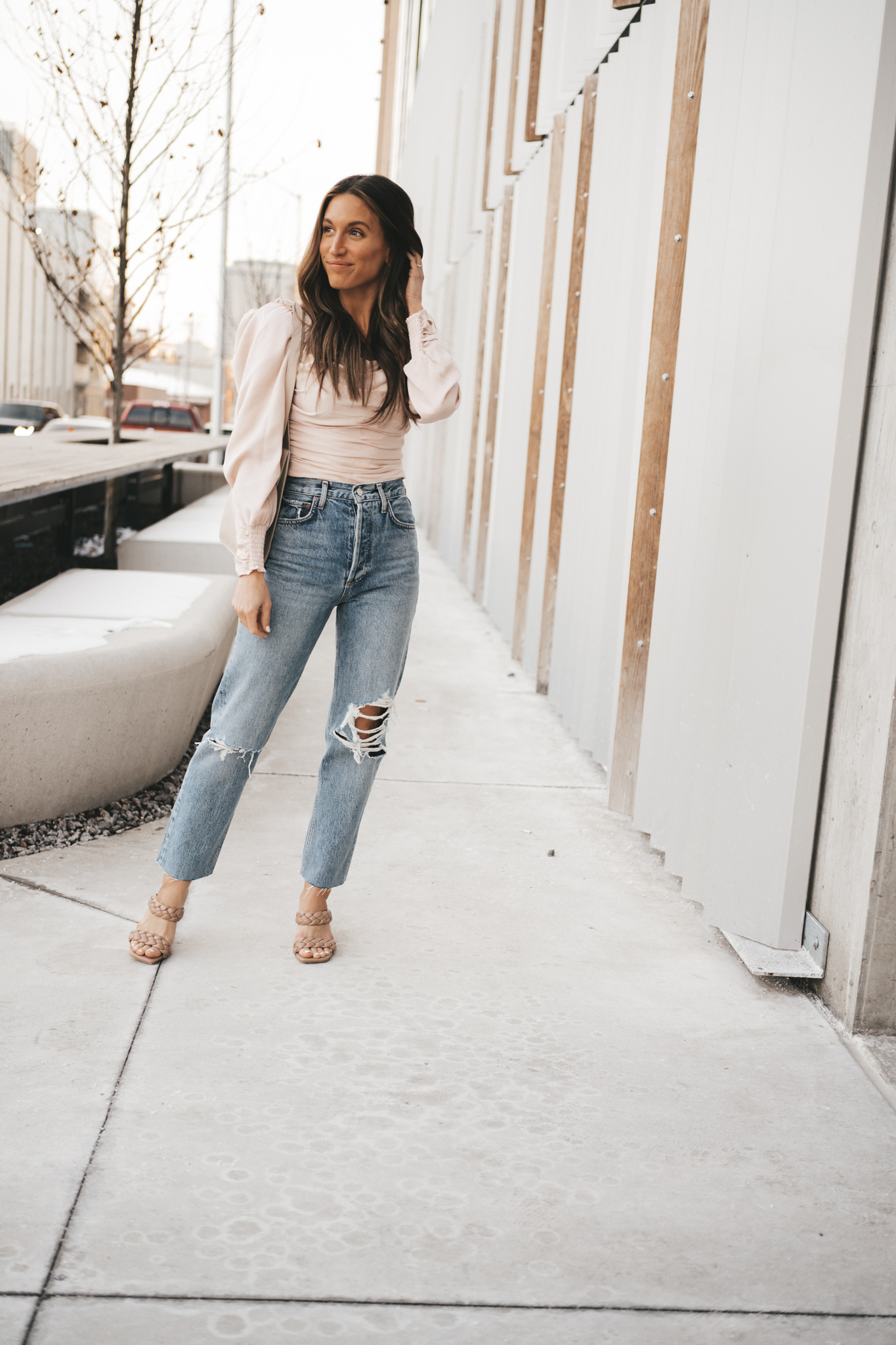 spring date night outfit with a blush ruched front top, distressed denim, and taupe heeled sandals