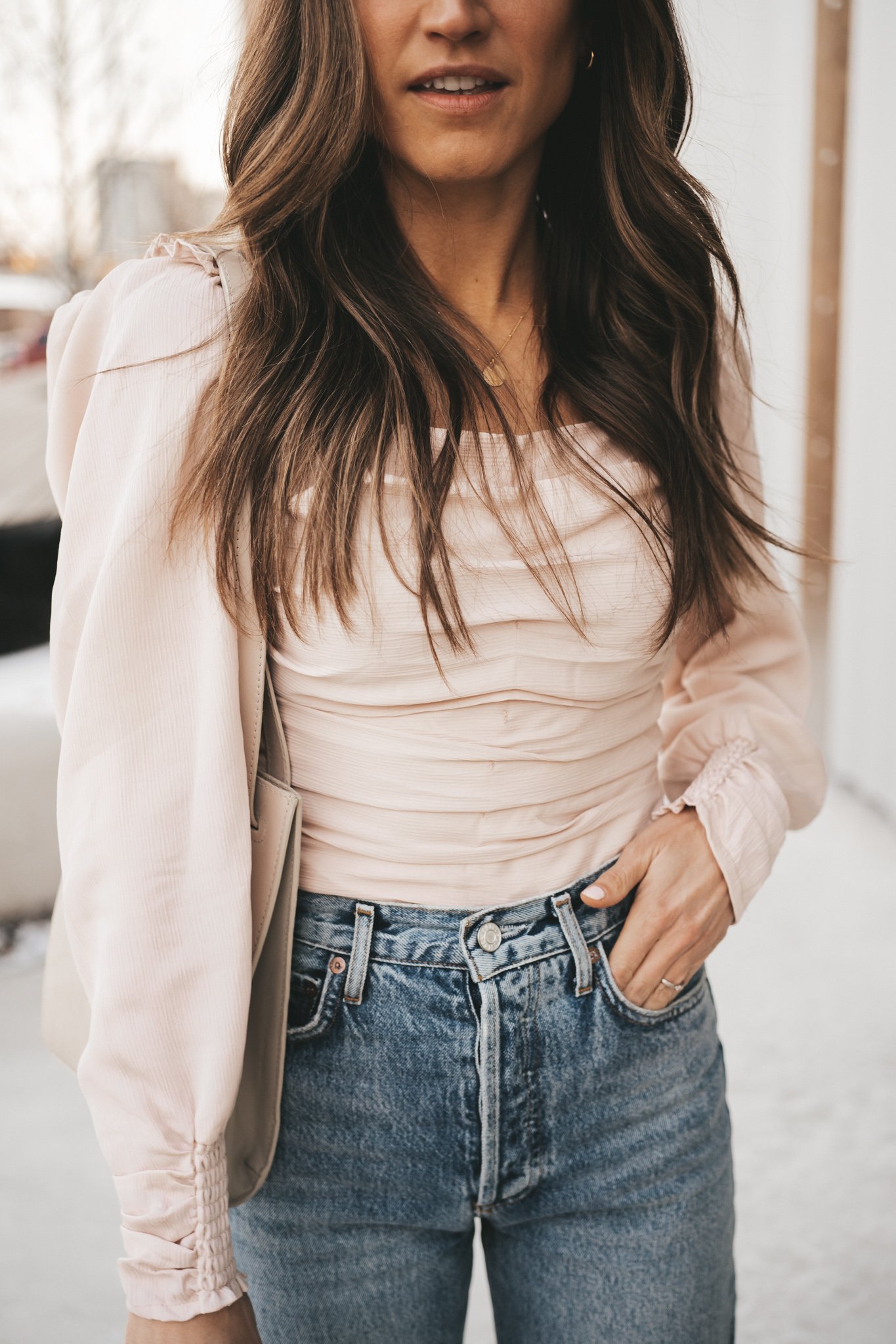 spring date night outfit with a blush ruched front top, distressed denim, and taupe heeled sandals
