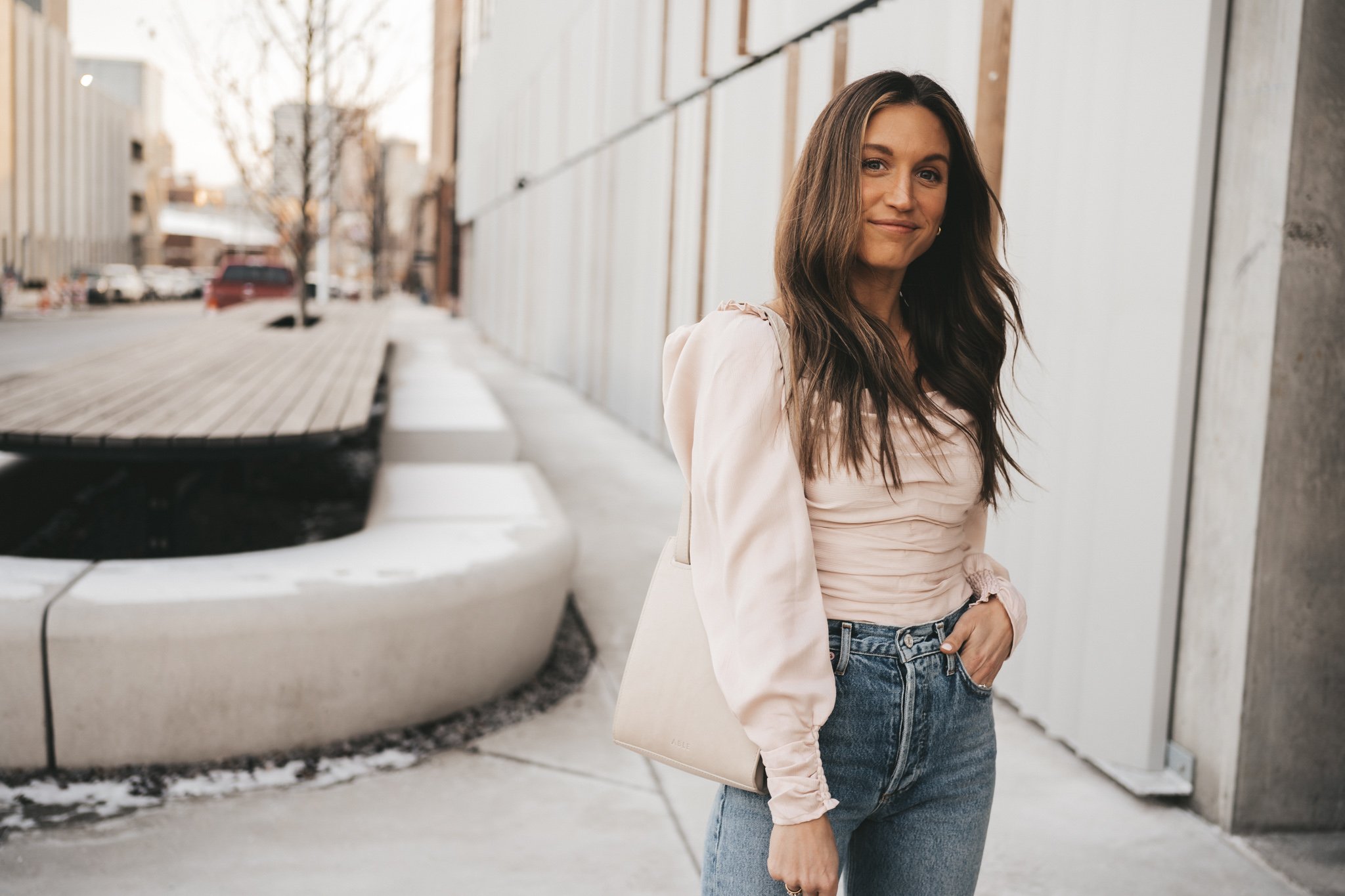 spring date night outfit with a blush ruched front top, distressed denim, and taupe heeled sandals