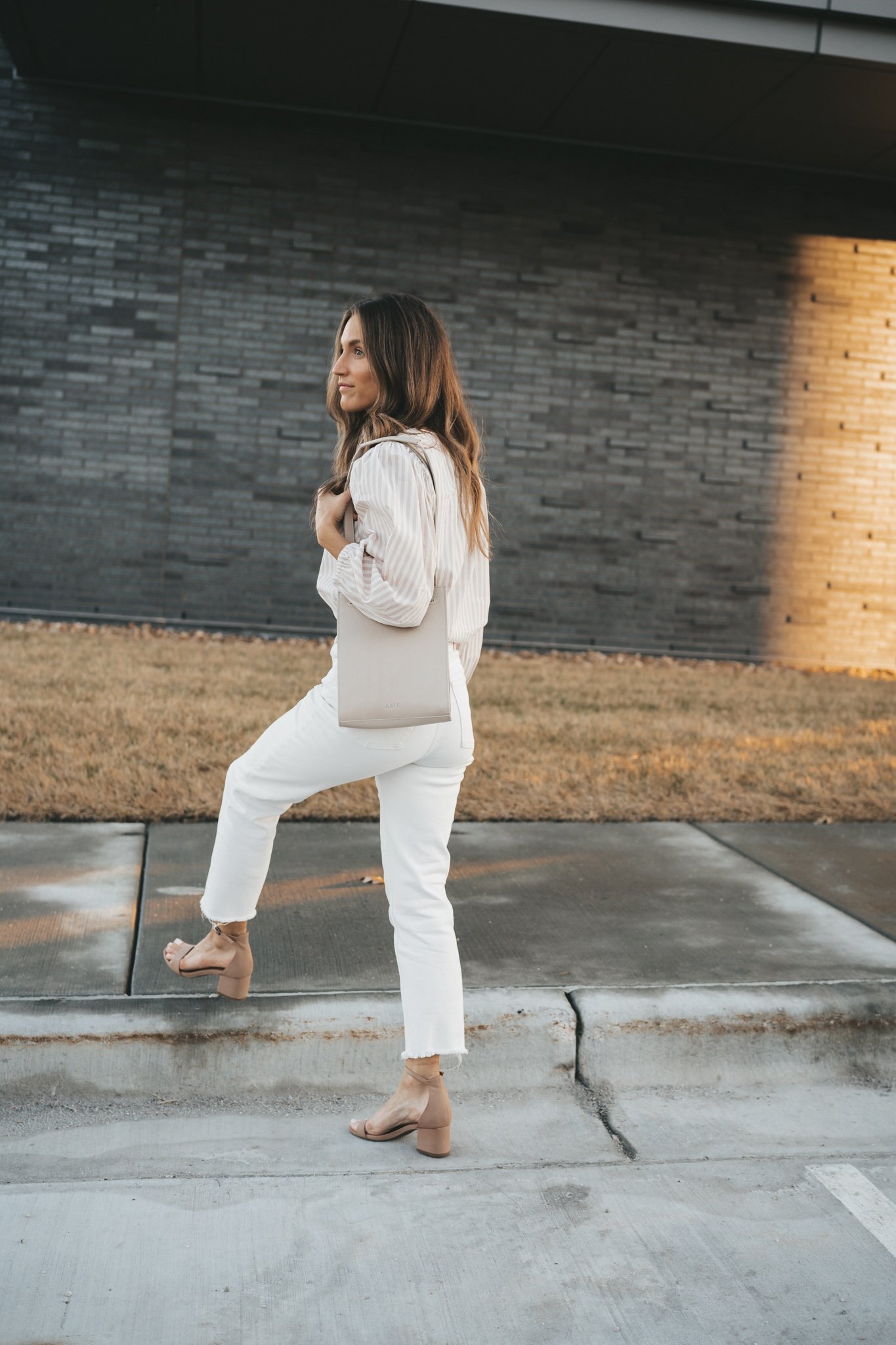 spring outfit with a striped blouse, white denim, and nude block heel sandals