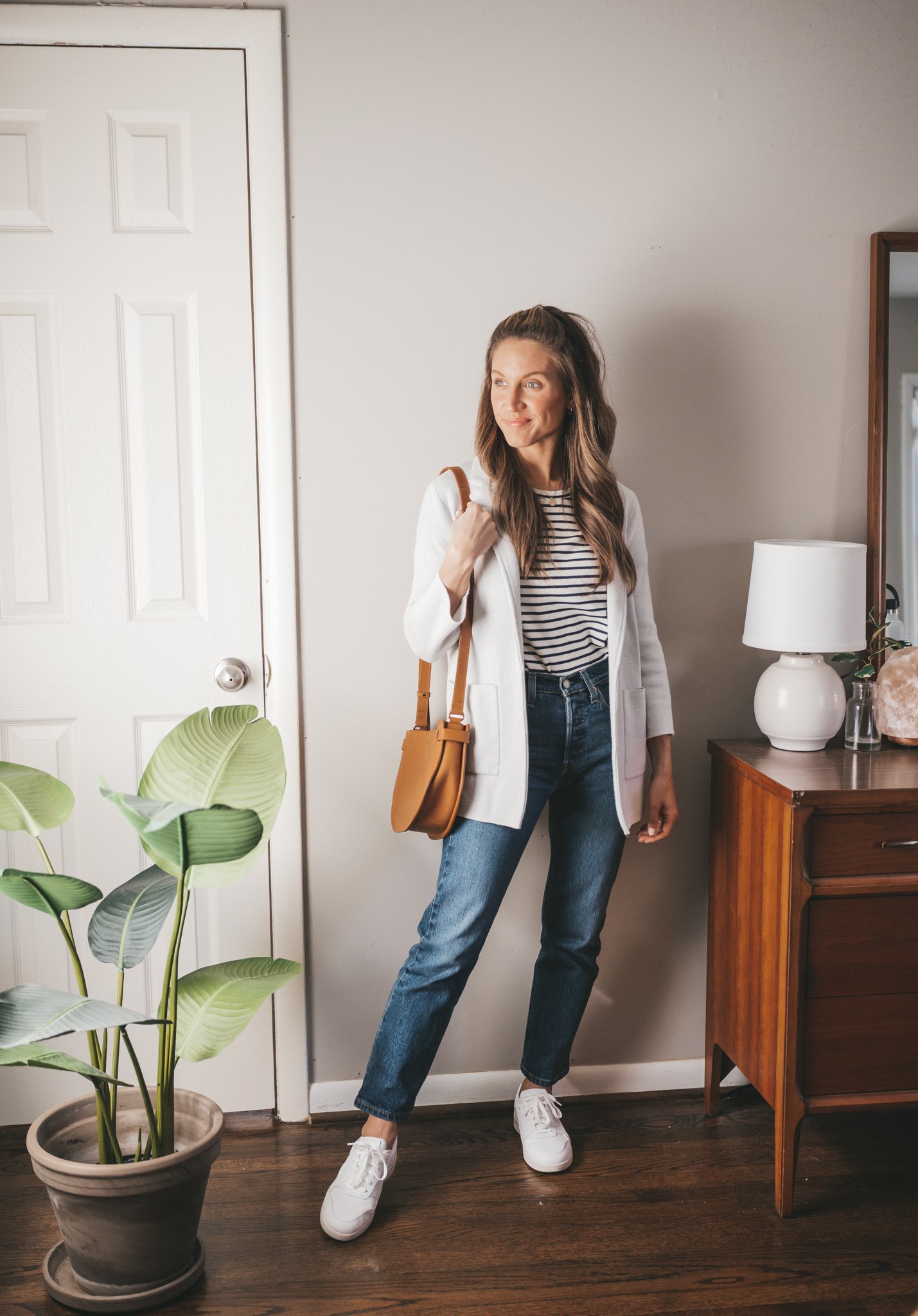 spring capsule wardrobe outfit with a striped tee, gray sweater blazer, mid-wash straight denim, and white sneakers with a cognac crossbody bag