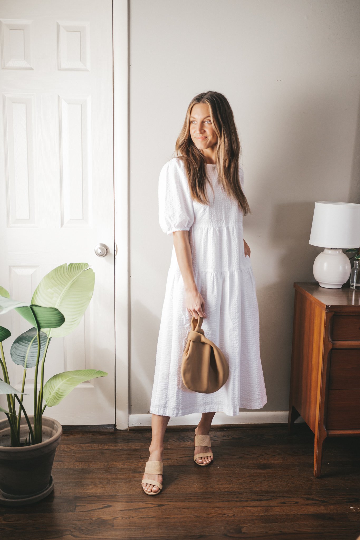 spring break outfit with a white midi dress, heeled woven sandals, and a tan clutch