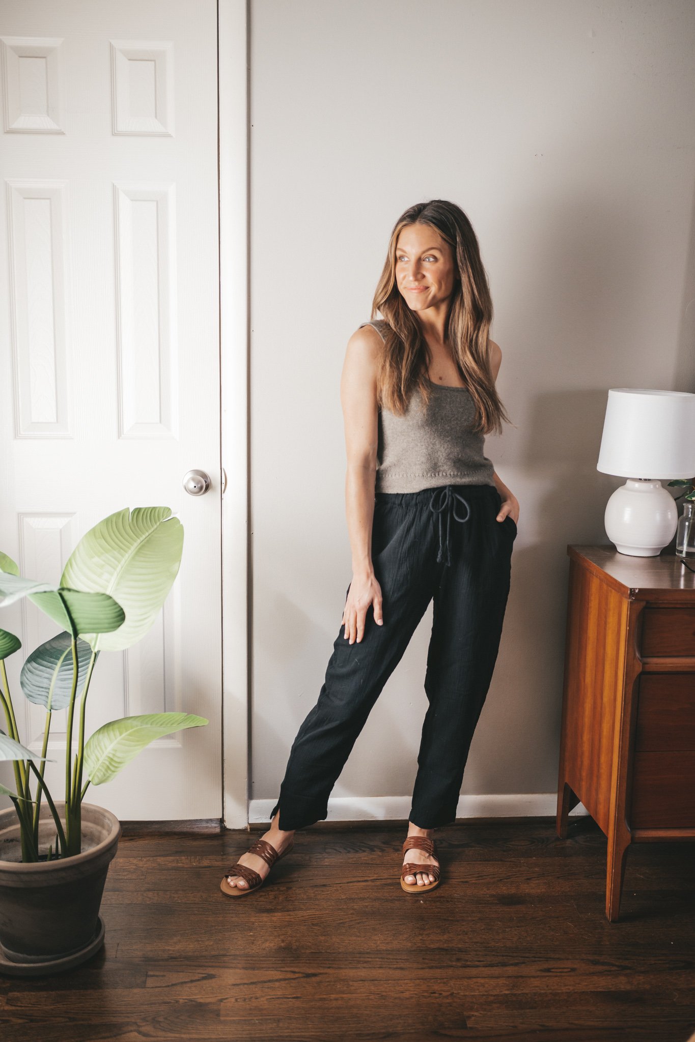 spring break outfit with a taupe cropped sweater tank, black gauze pants, and braided sandals