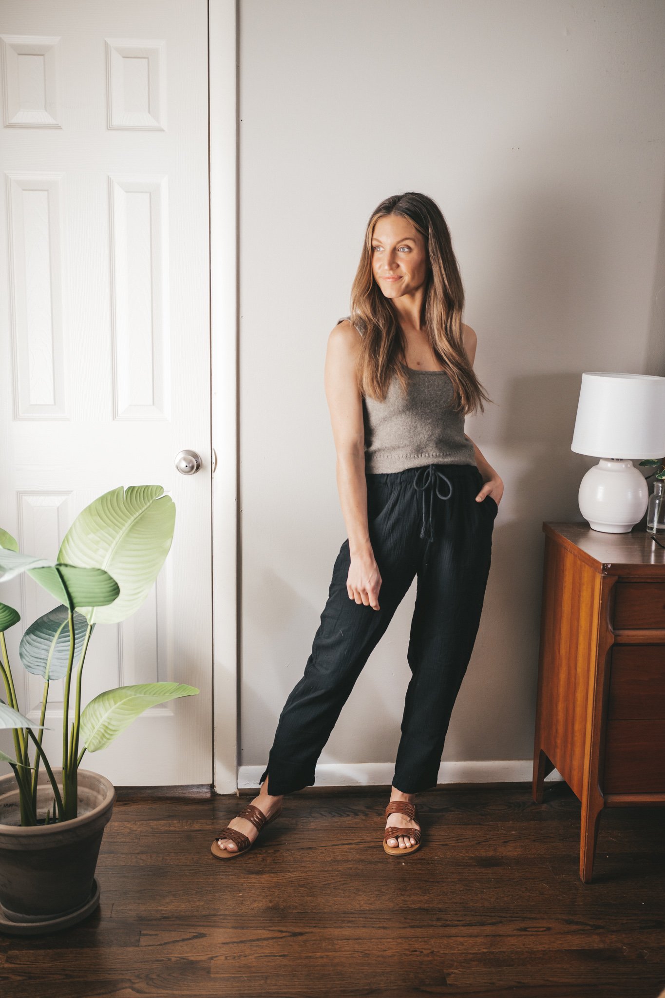 spring break outfit with a taupe sweater tank, black gauze pants, and braided sandals