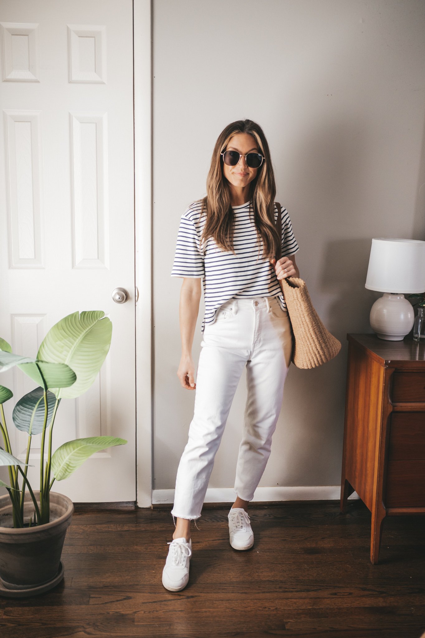 spring break outfit with a white and navy striped tee, white denim, and white sneakers