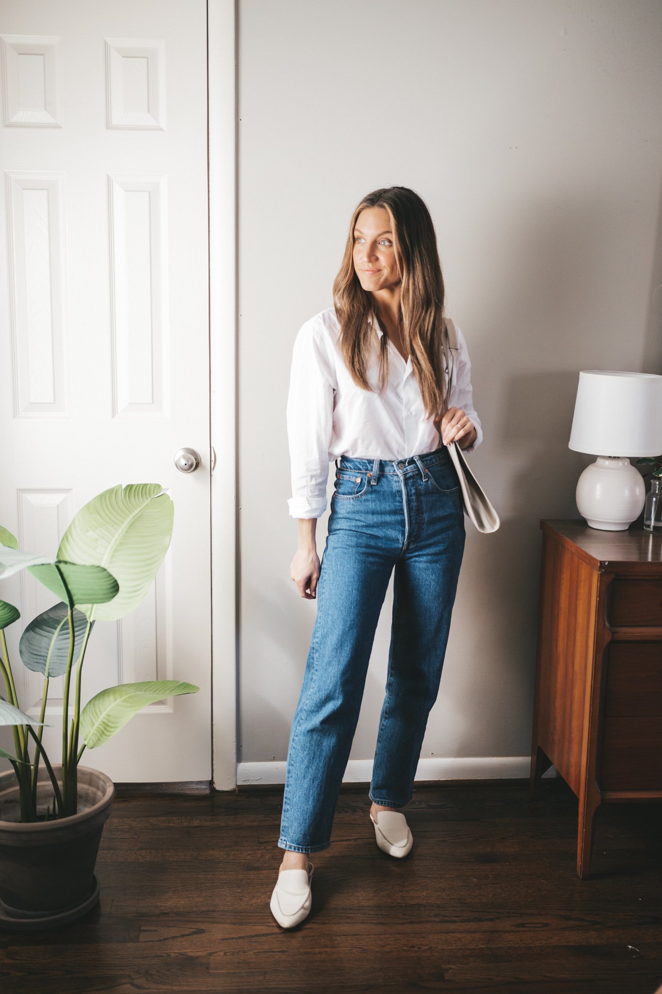 outfit from my spring capsule wardrobe with a white button down, mid-wash straight denim, white mules and a gray shoulder bag
