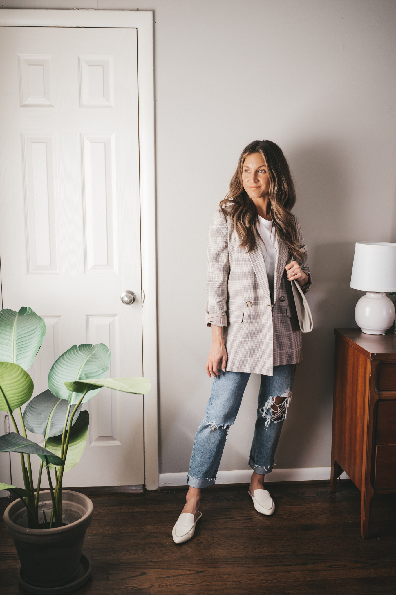 spring capsule wardrobe outfit with a white tee, light plaid blazer, distressed denim, and white mules
