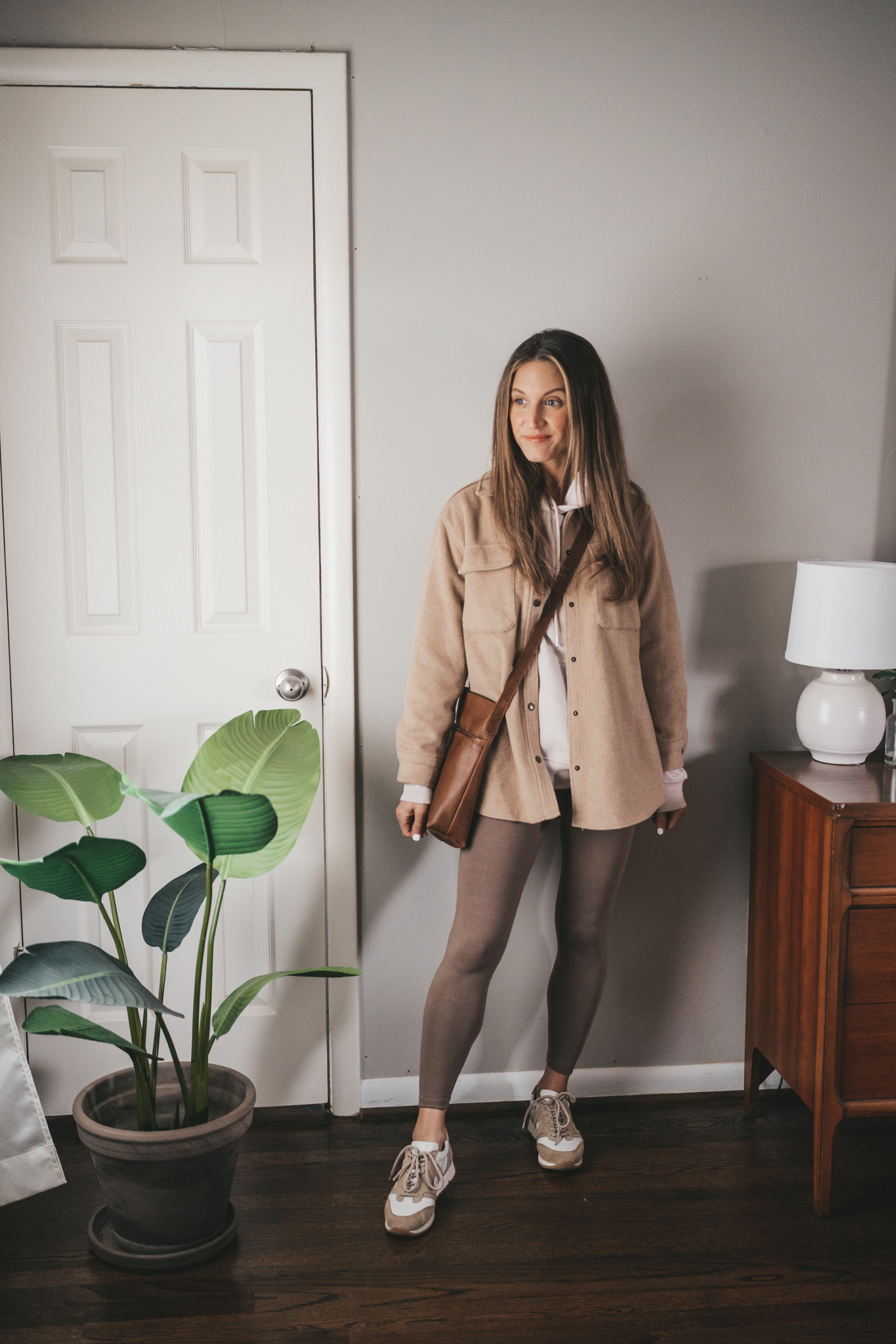 spring outfit with a taupe hoodie, tan shacket, taupe leggings, and white and tan sneakers